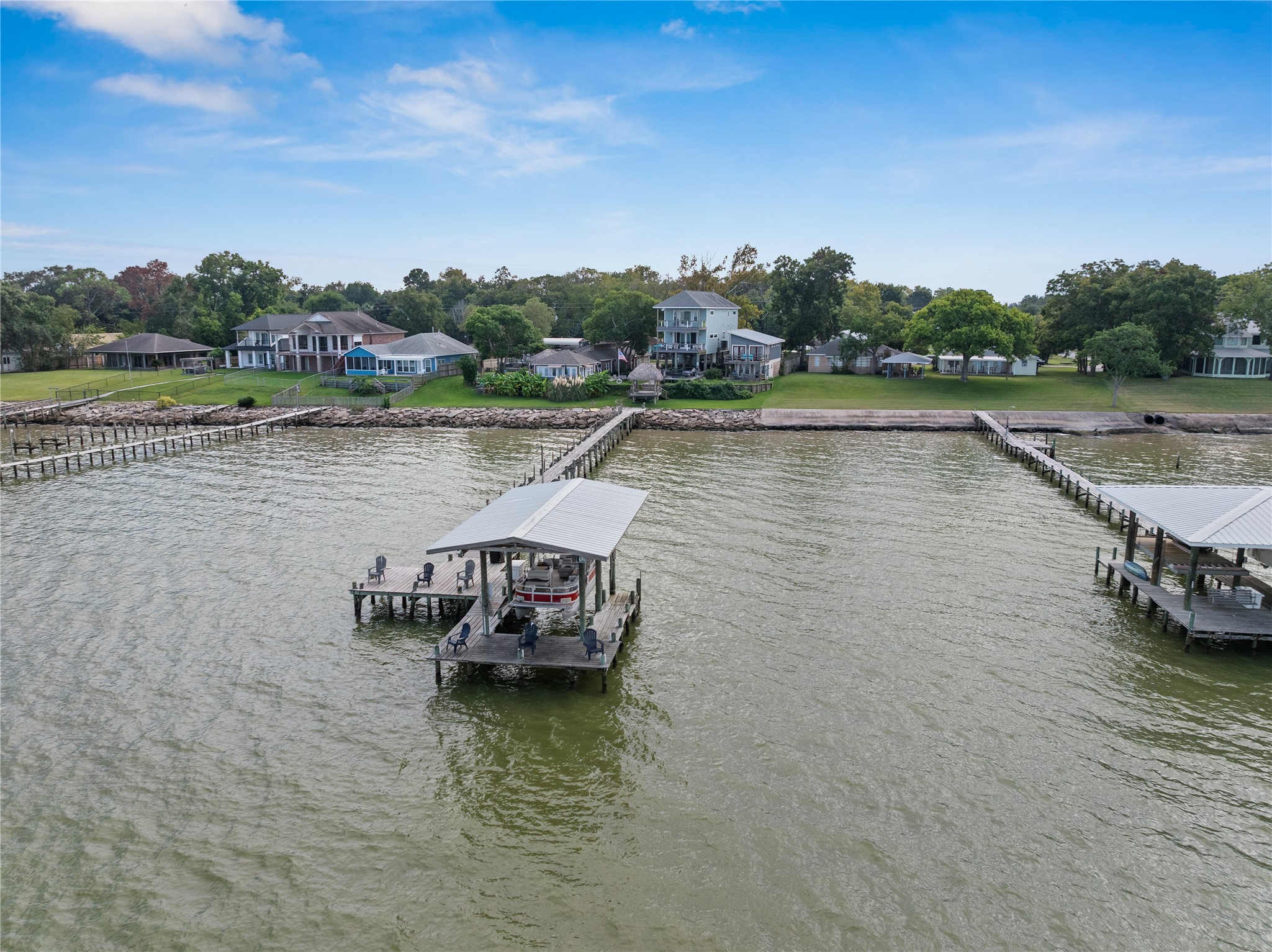 This photo showcases the serene waterfront property with a private pier extending into Galveston Bay. The area features well-maintained houses and lush greenery, offering a peaceful and picturesque setting ideal for relaxation and leisure activities.