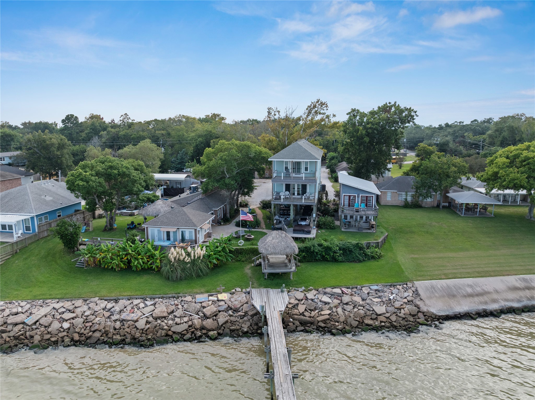 Charming waterfront property with a spacious lawn, lush landscaping, and a private pier extending into the water.