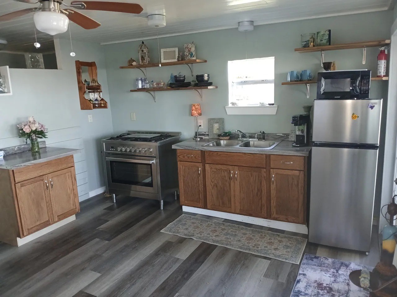 Charming kitchen in the La View with ample natural light and modern appliances, featuring open shelving and stylish wood cabinetry. Perfect for culinary enthusiasts!