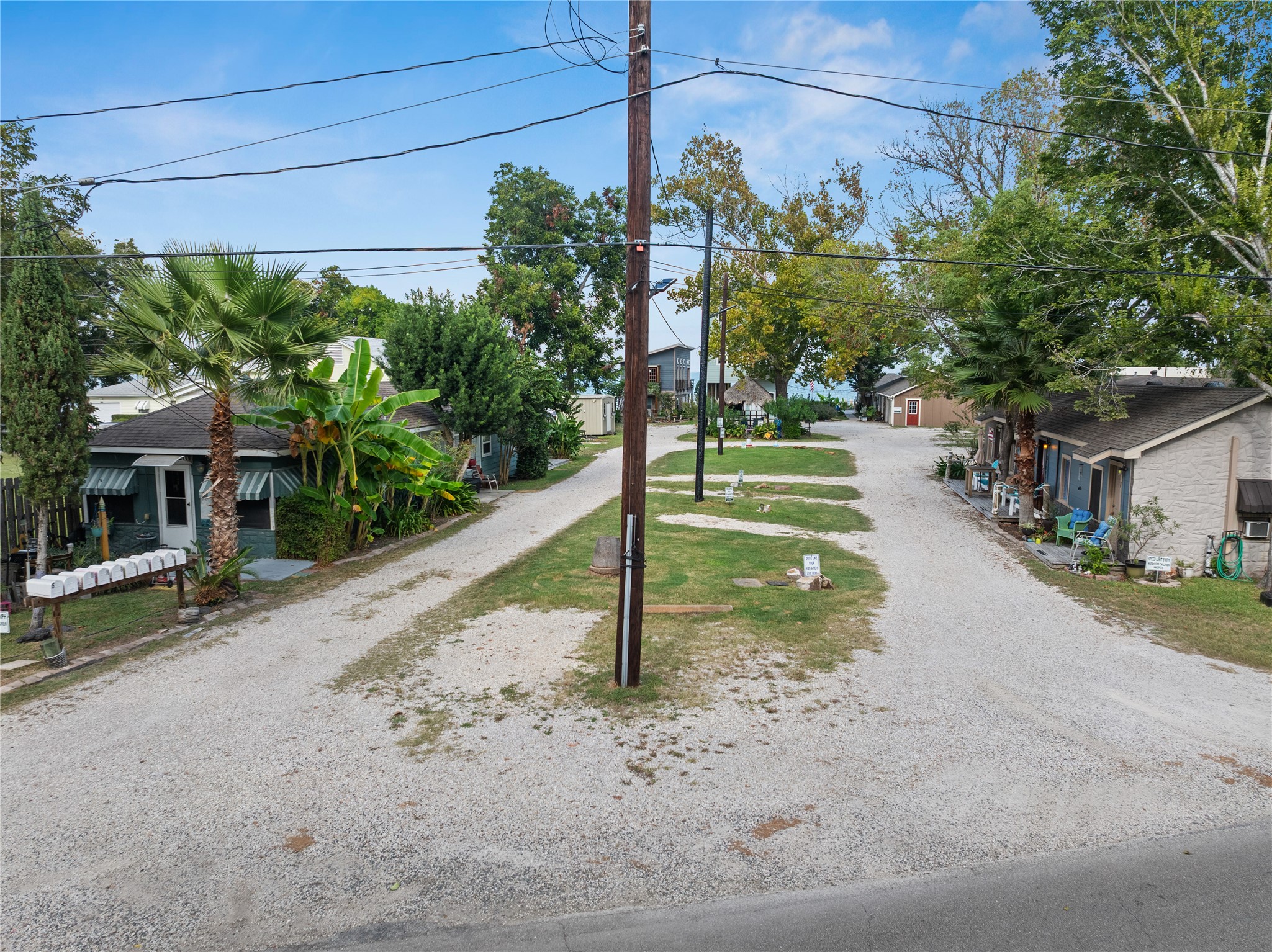 This photo shows a quaint property with small homes lining a gravel road. The street is flanked by trees and greenery, creating a cozy atmosphere.