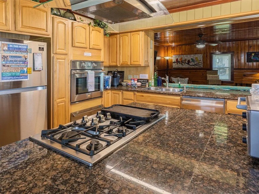 Inviting kitchen in the Ohana House with sleek granite countertops, a modern gas stove, and warm wooden cabinetry, perfect for culinary enthusiasts.