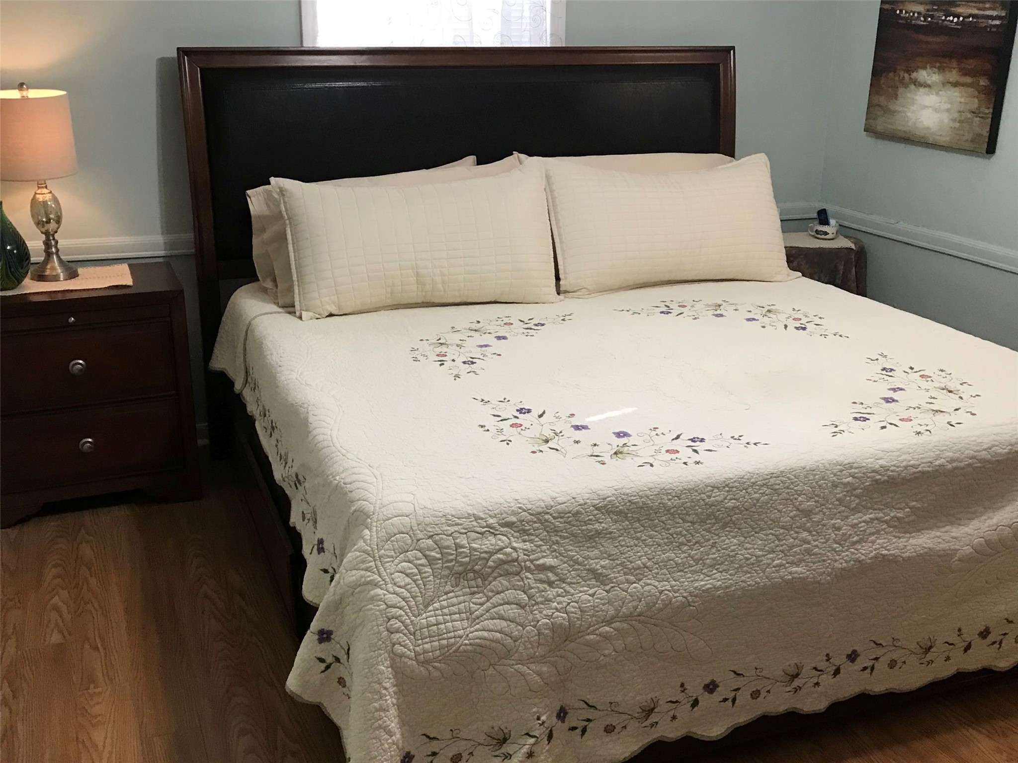Cozy bedroom in Annie's Song featuring a plush bed with an elegant embroidered coverlet, accompanied by warm lighting and tasteful decor. Perfect for relaxation and comfort.