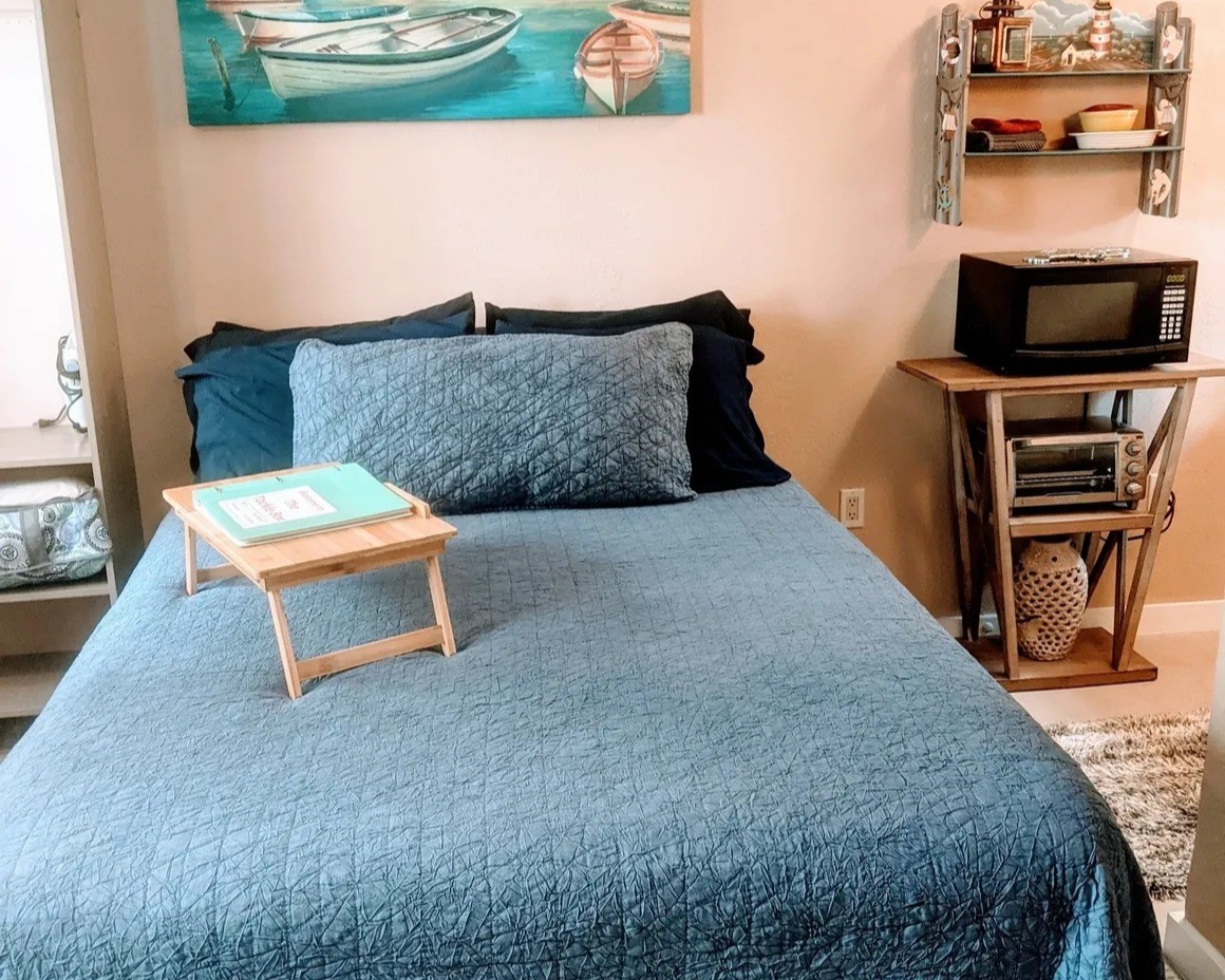 Charming bedroom in the Tackle Box with cozy decor, featuring nautical accents and convenient amenities like a microwave and toaster oven. Perfect for relaxation and functionality.