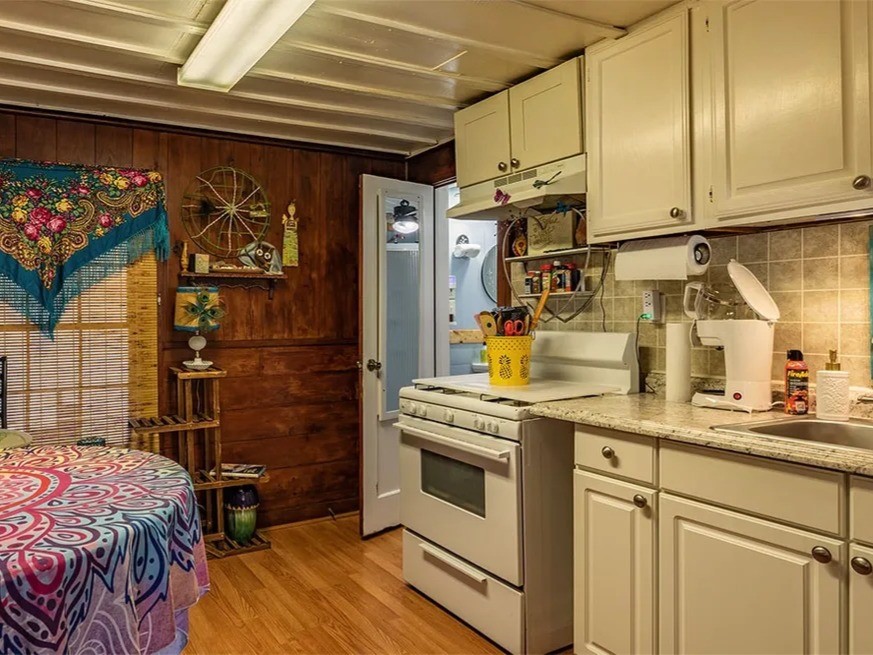 Cozy and charming kitchen in the Saltwater Gypsy featuring rustic wood paneling and modern cabinetry, creating a unique blend of style and functionality. Perfect for creative cooking and intimate gatherings.