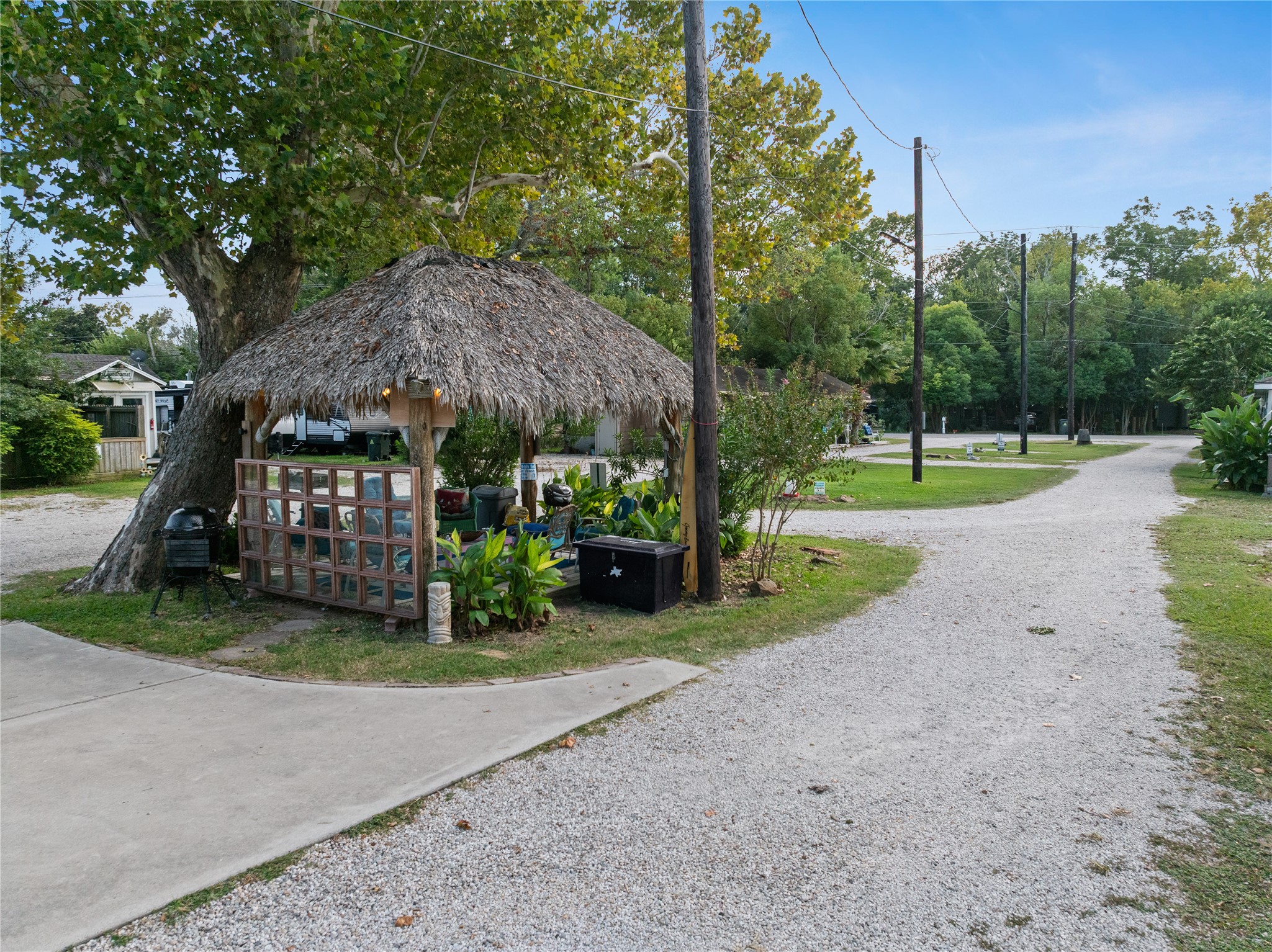 This photo showcases a serene outdoor setting featuring a gravel path, lush greenery, and a charming palapa. It's an inviting space ideal for relaxation and enjoying nature.