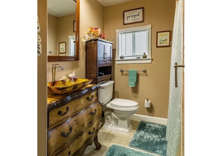 Experience elegance in the Ohana House bathroom, featuring a stylish vessel sink, rich wooden cabinetry, and serene neutral tones.