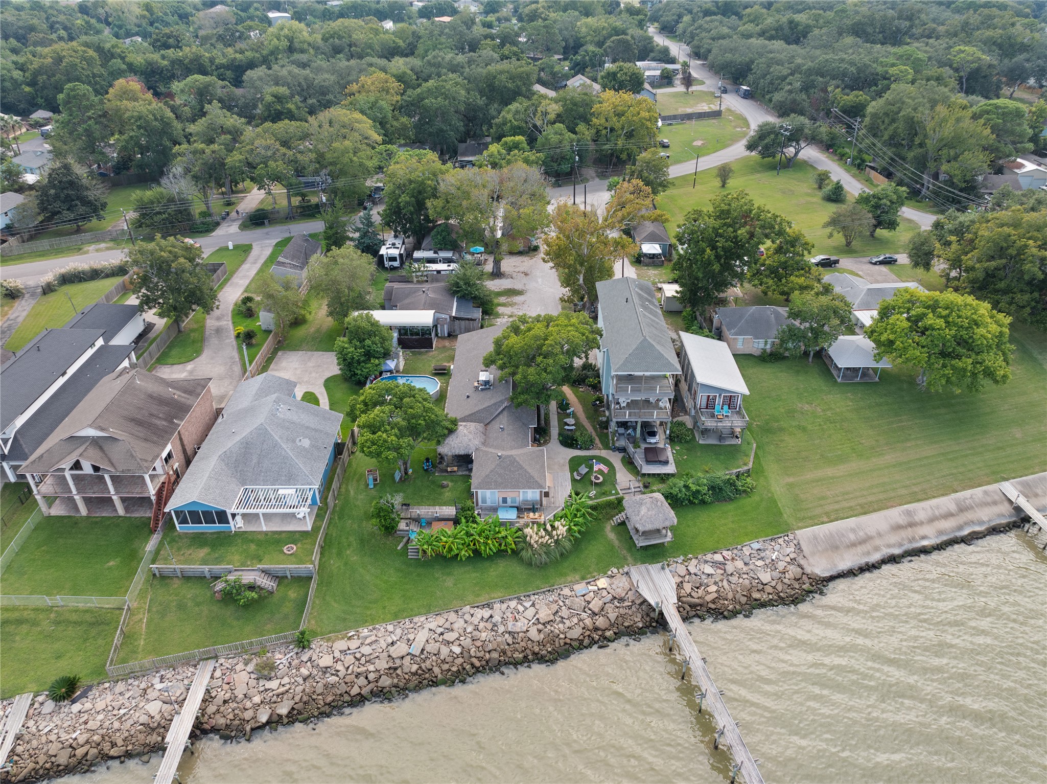 This aerial photo showcases a row of charming waterfront homes adjacent to the subject property with spacious yards and direct access to the shoreline. The neighborhood appears tranquil, with well-maintained properties and a mix of architectural styles.