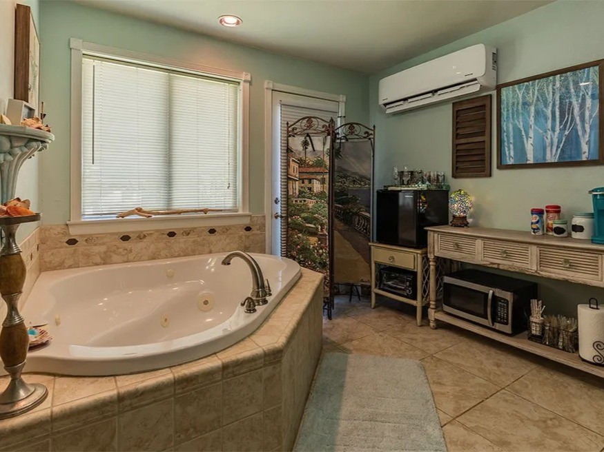 Experience relaxation and style in this elegant Ohana House bathroom, featuring a luxurious soaking tub and charming decor.