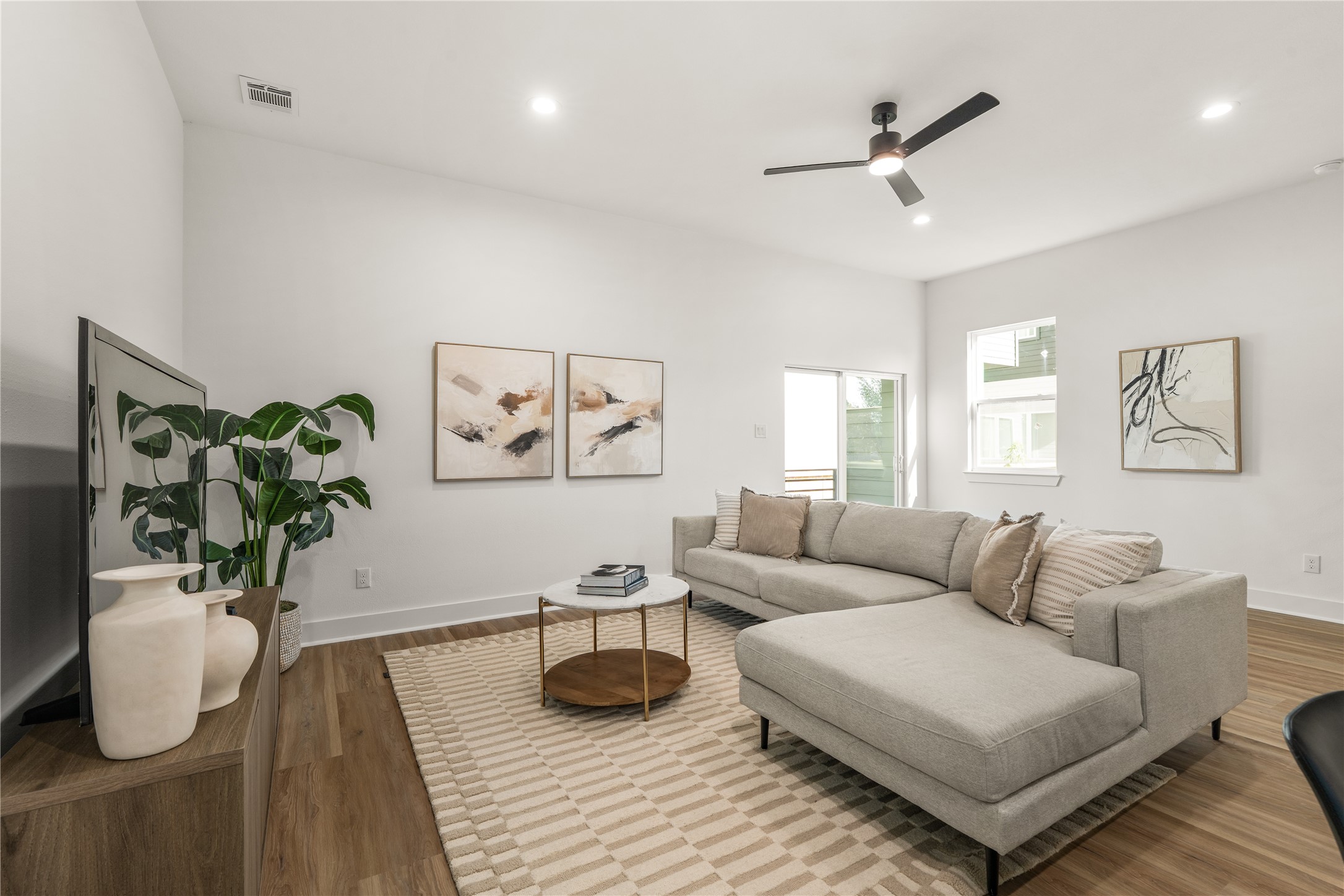 Soft light from the window and sliding door warms the living room, where clean white walls and generous
proportions make it easy to create a relaxed, personalized retreat.