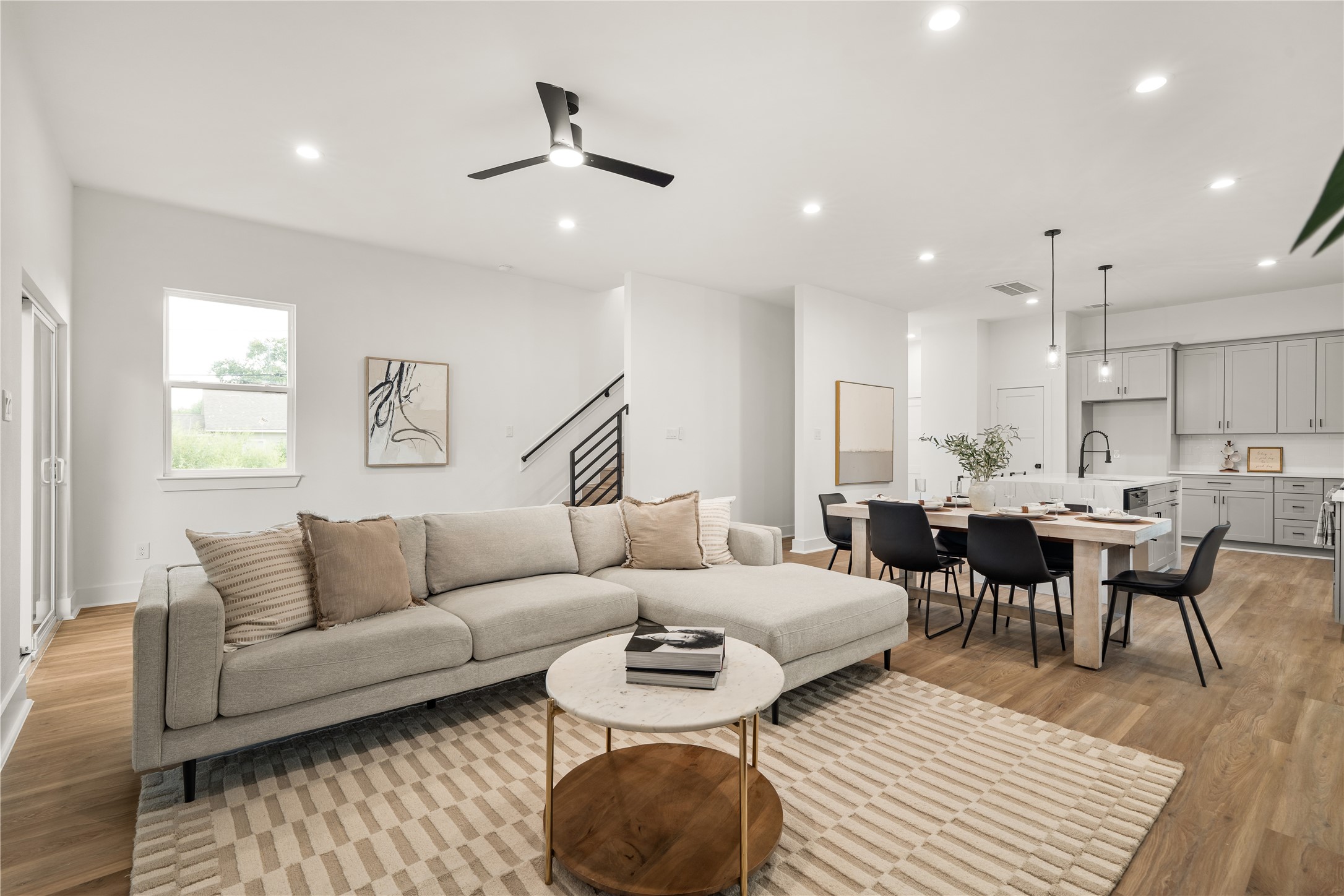 The living area anchors the home, with the staircase's horizontal black railing adding a bold graphic
element as the space opens effortlessly to the dining room and kitchen.