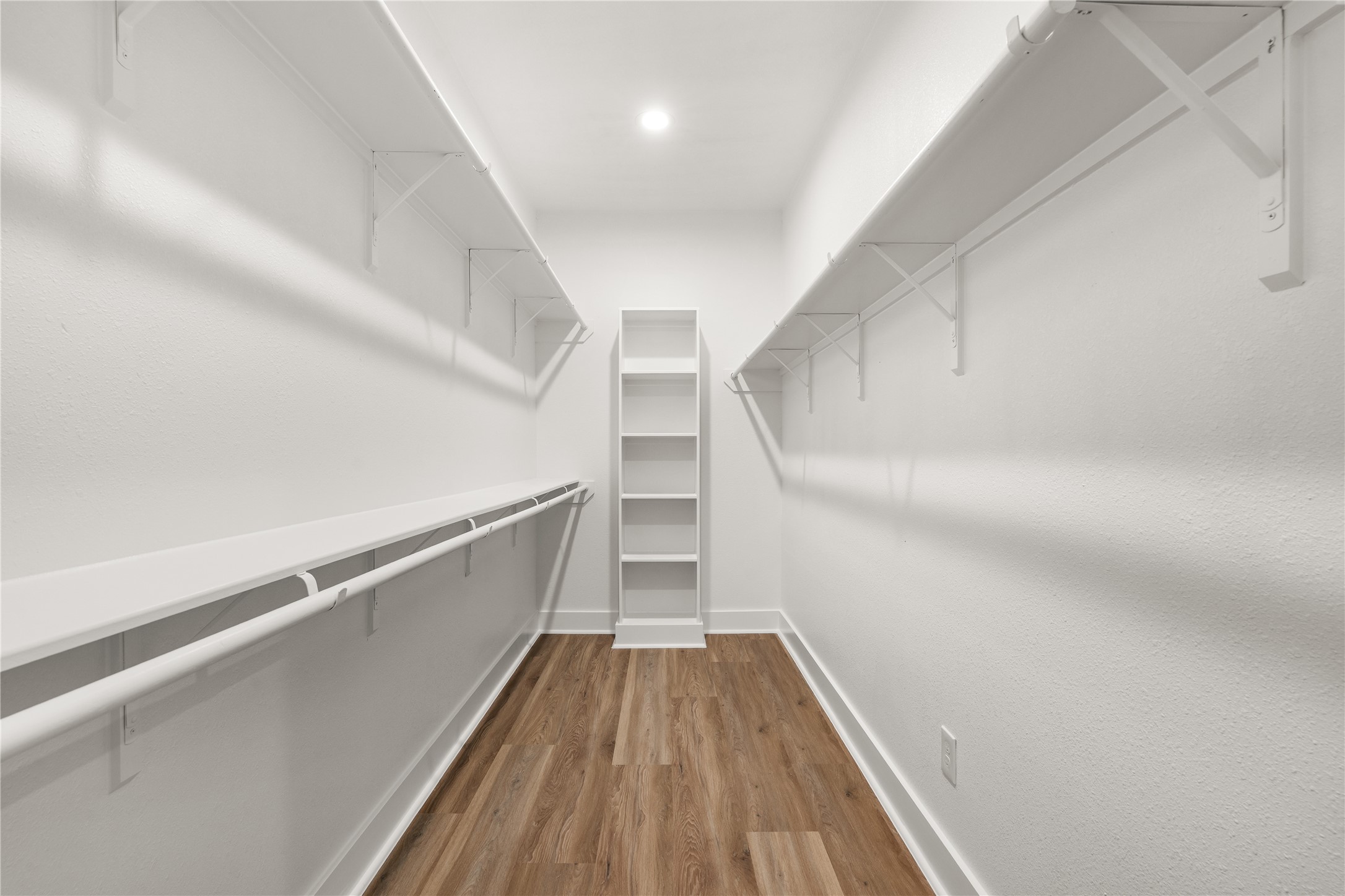 A spacious walk-in closet delivers organized storage, with multi-level hanging rods and shelving along
both walls, finished by a built-in shelving tower at its center.