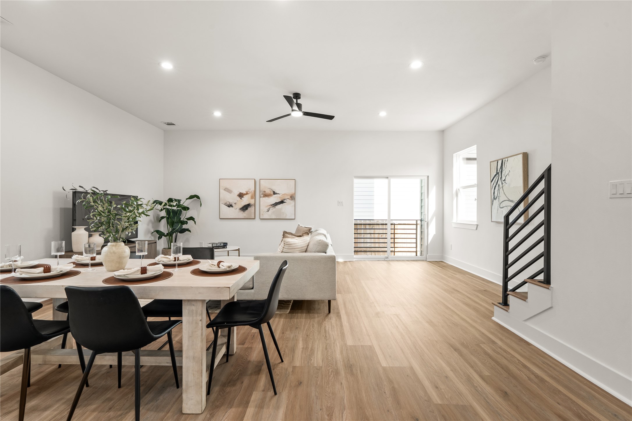 The dining and living spaces flow together beneath recessed lighting, while a sliding glass door and a
modern black-railed staircase bring both light and architectural interest to the main level.