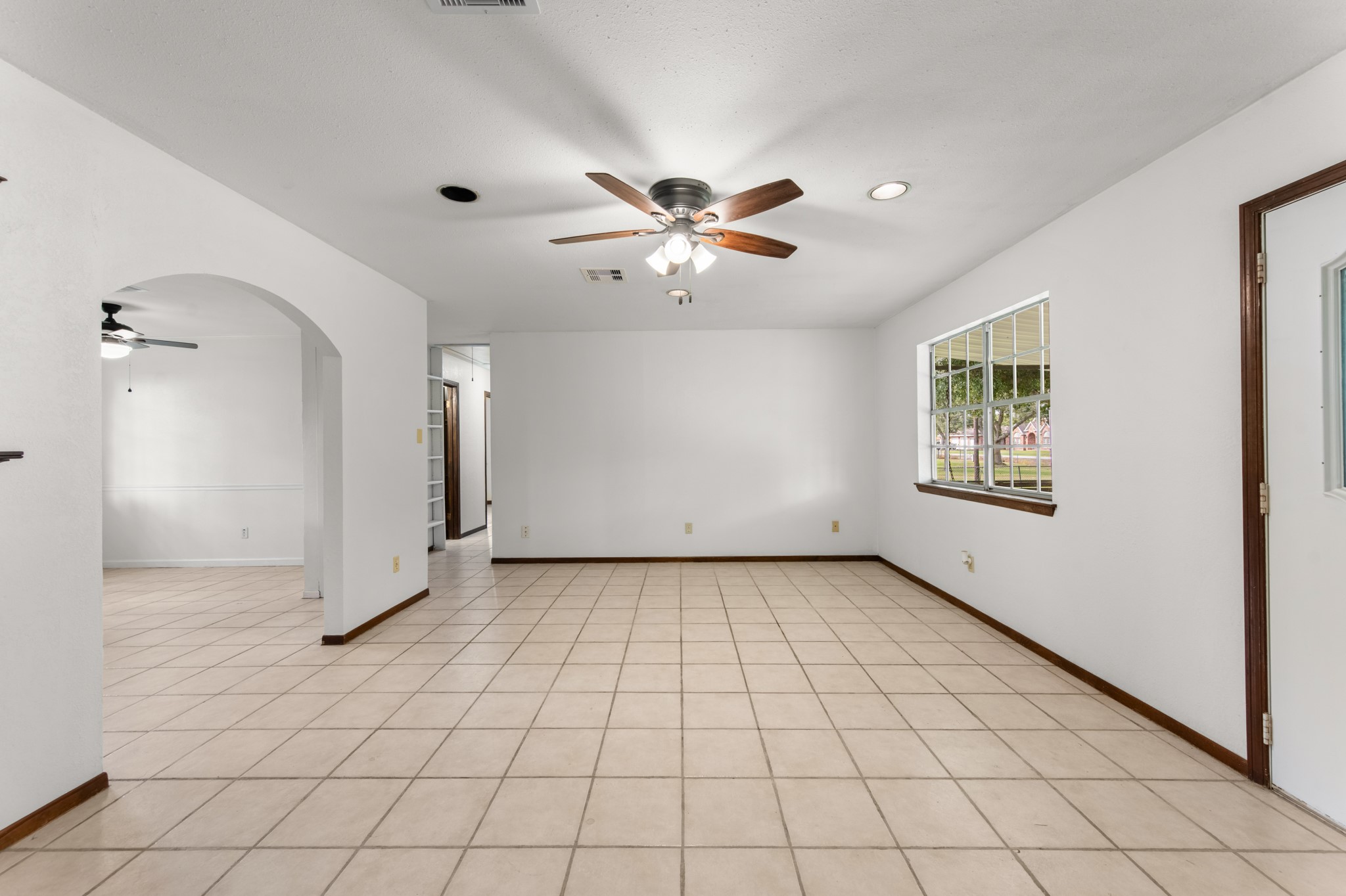 Bright and versatile living space offering flexible furniture arrangements, recessed ceiling lighting, and easy access to the adjoining dining area and hallway.