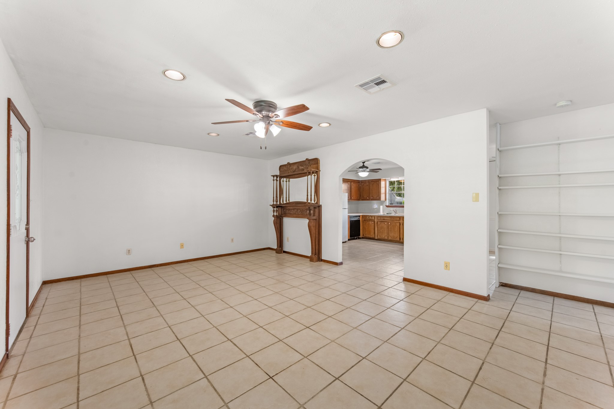 An arched opening connects the living room to the kitchen, creating a welcoming flow between the home's main gathering spaces. Built-in shelving provides additional display and storage options.