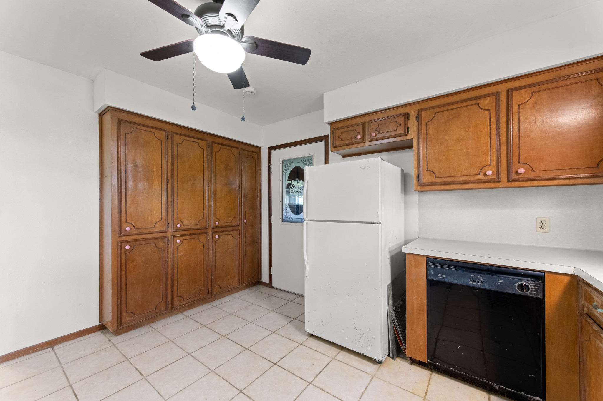 Floor-to-ceiling pantry-style cabinetry offers exceptional storage for kitchen essentials, cookware, and pantry items, complemented by additional upper and lower cabinets.