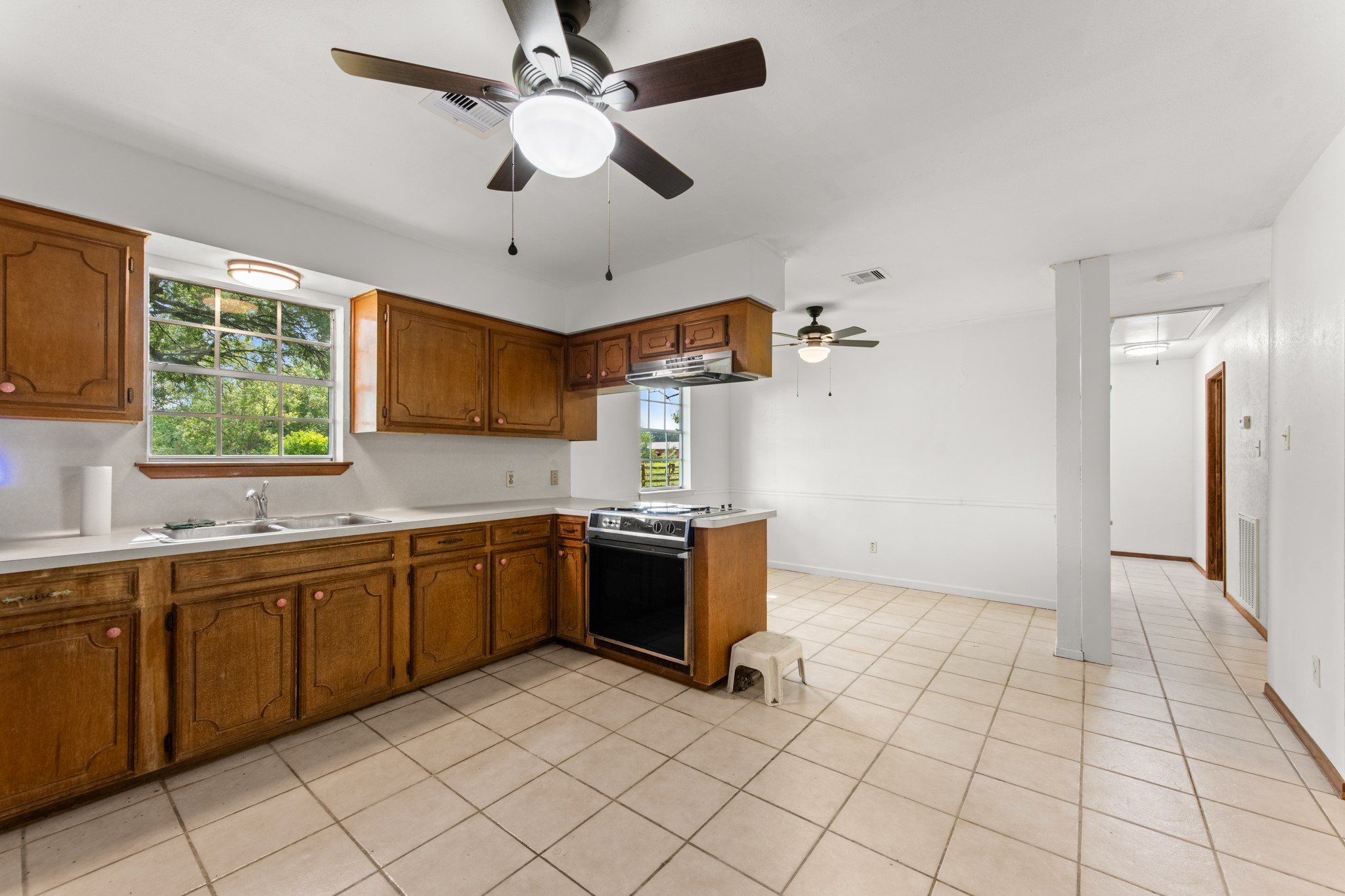 Natural light pours through the kitchen window above the double-basin sink, while the adjoining dining area provides an easy flow for everyday meals and entertaining.