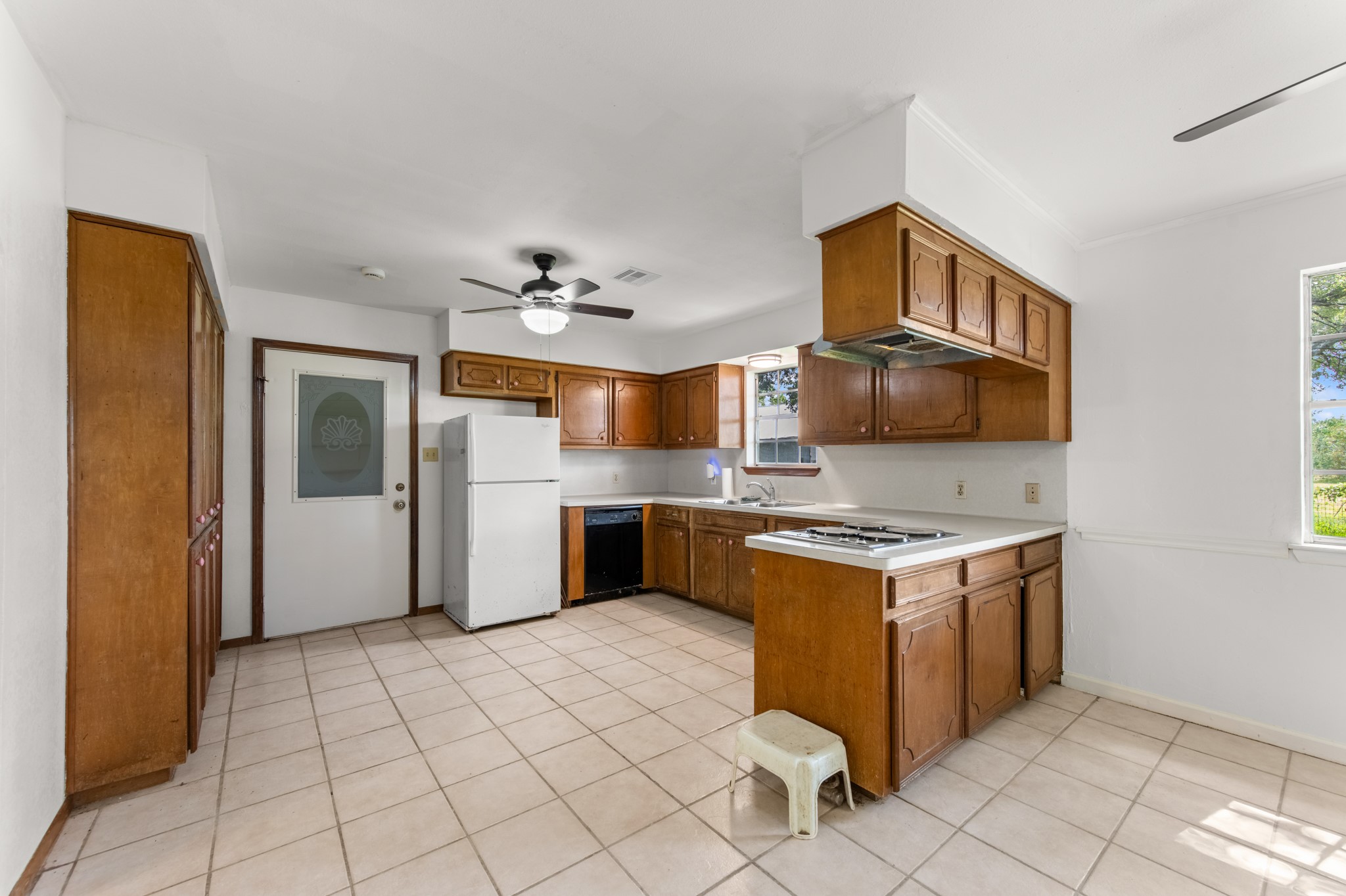 Spacious kitchen featuring abundant wood cabinetry, generous counter space, tile flooring, and a convenient layout with an adjoining dining area.