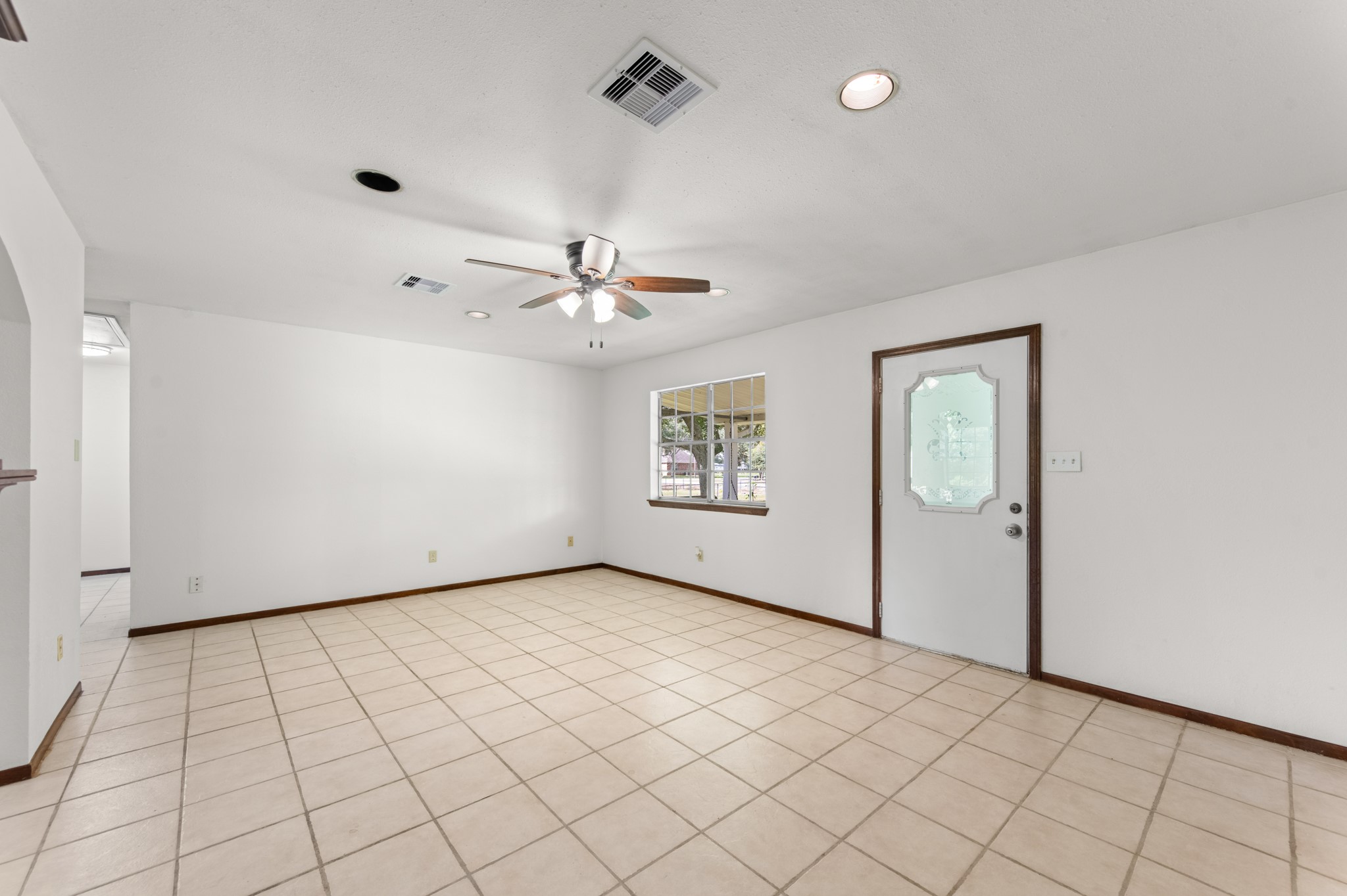 An inviting living area with a large front-facing window, decorative glass entry door, and plenty of room for comfortable seating and entertaining.