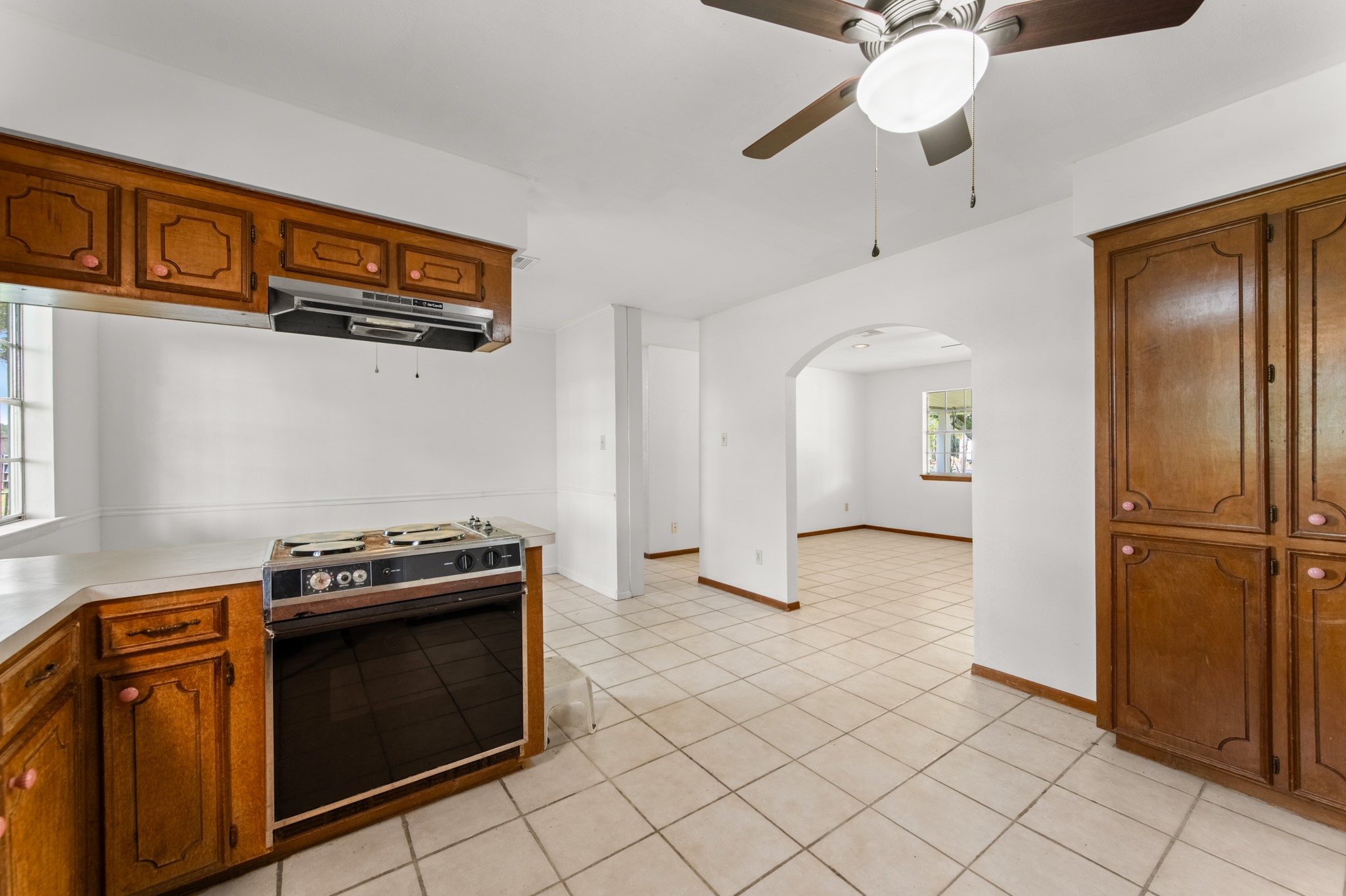 A view from the kitchen highlights the electric range, additional cabinet storage, and charming arched doorway connecting to the adjacent living space.