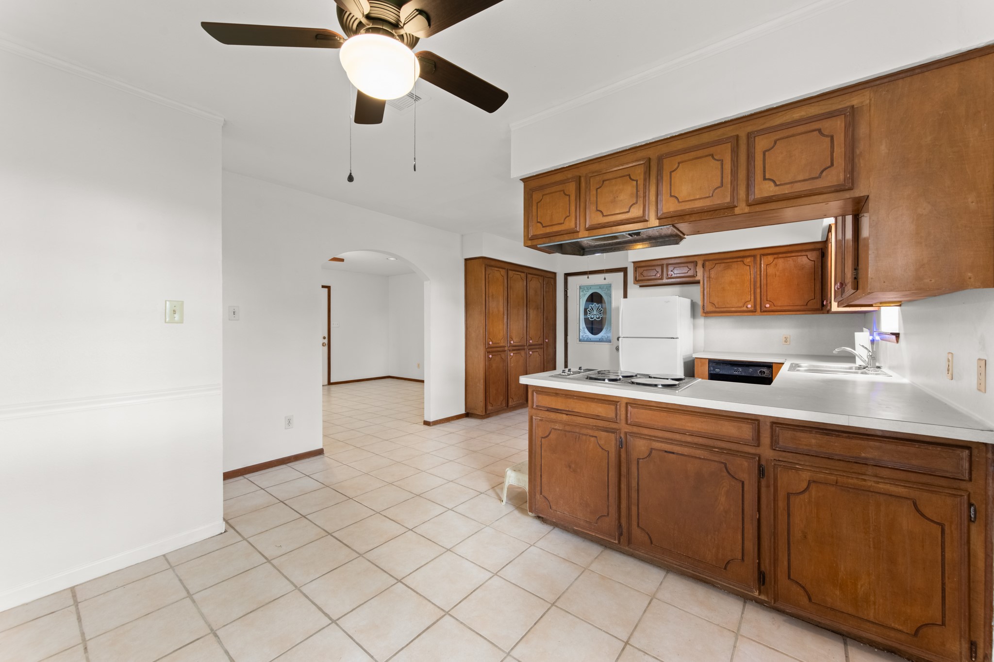 The dining area flows conveniently into the kitchen, featuring warm wood cabinetry, a breakfast bar, and an arched opening connecting to the adjacent living space.