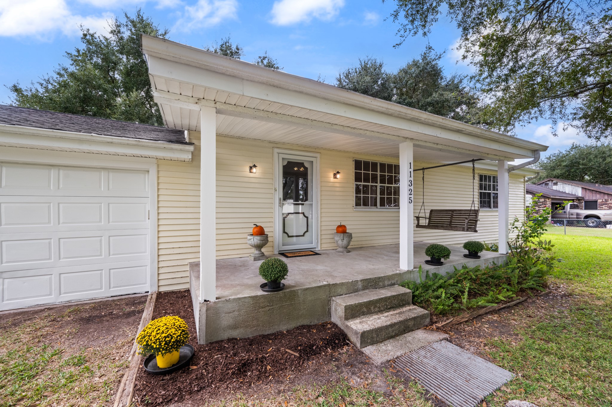Welcoming covered front porch featuring a porch swing, landscaped flower beds, and an inviting entryway. A charming spot to relax and enjoy the outdoors.