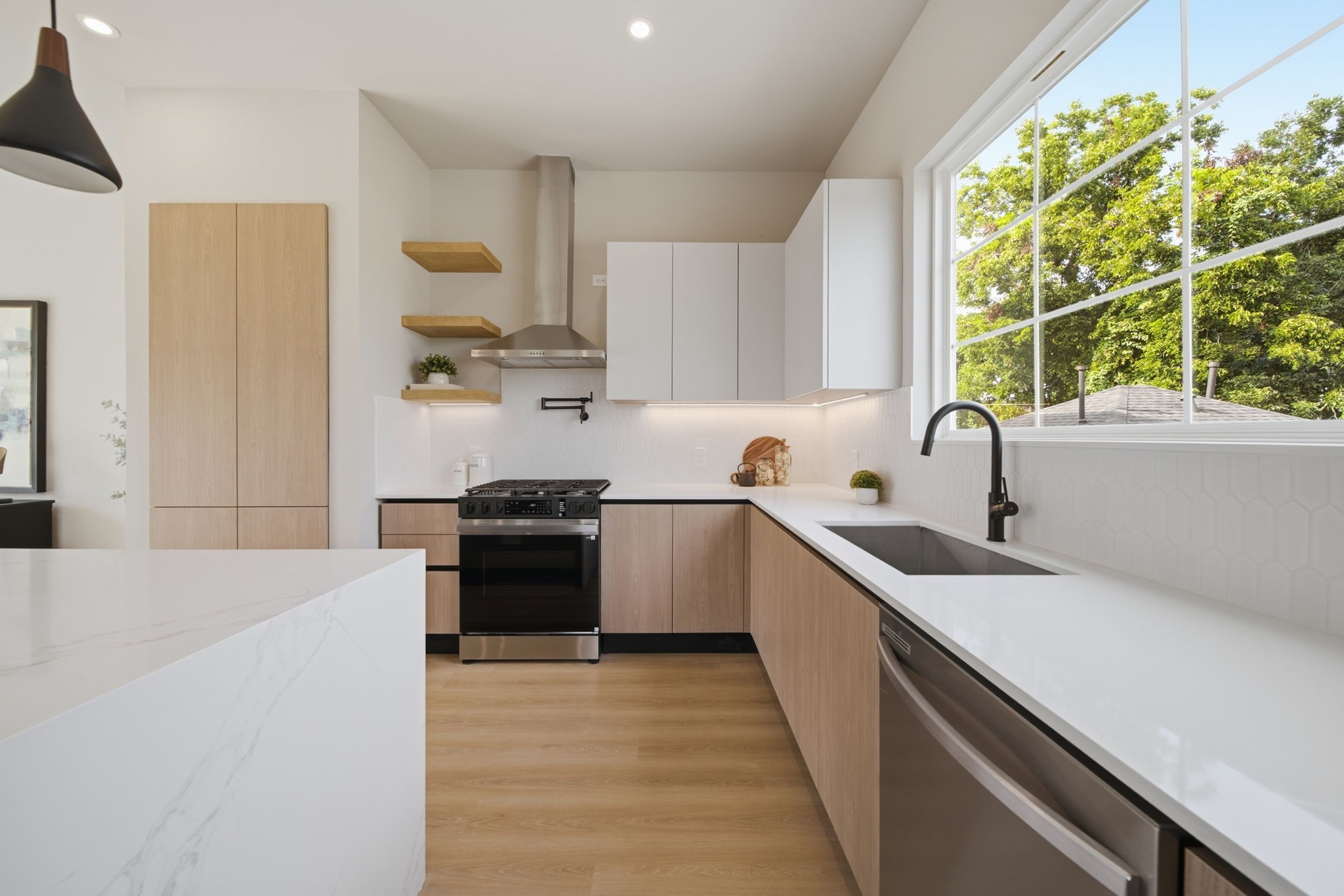 Kitchen is equipped with quartz countertops, flat cabinets, and a waterfall island.