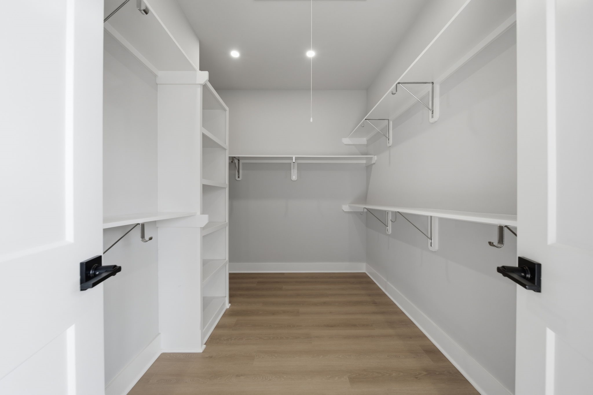 Large walk-in closet for the primary bedroom suite with builtin shelving and high ceilings.