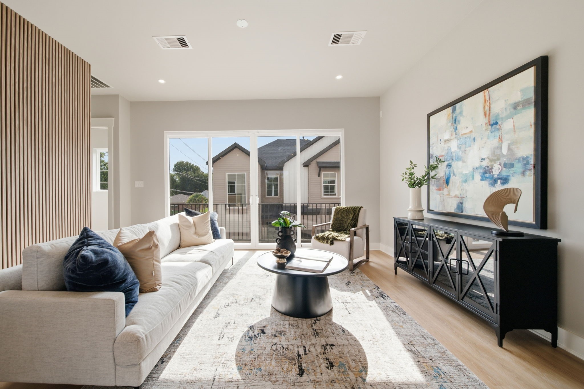 Beautiful living area with a ribbed accent wall and lots of natural light flooding throughout.