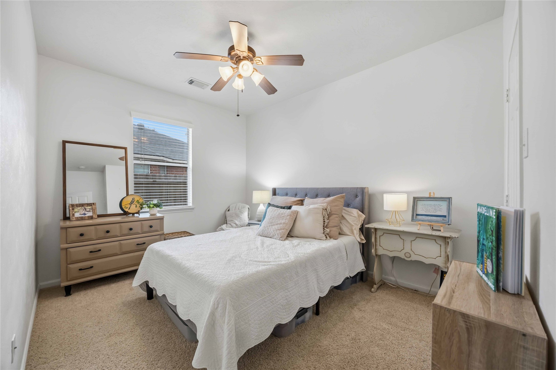Bright secondary bedroom featuring neutral carpeting, a ceiling fan, and a window providing natural light.