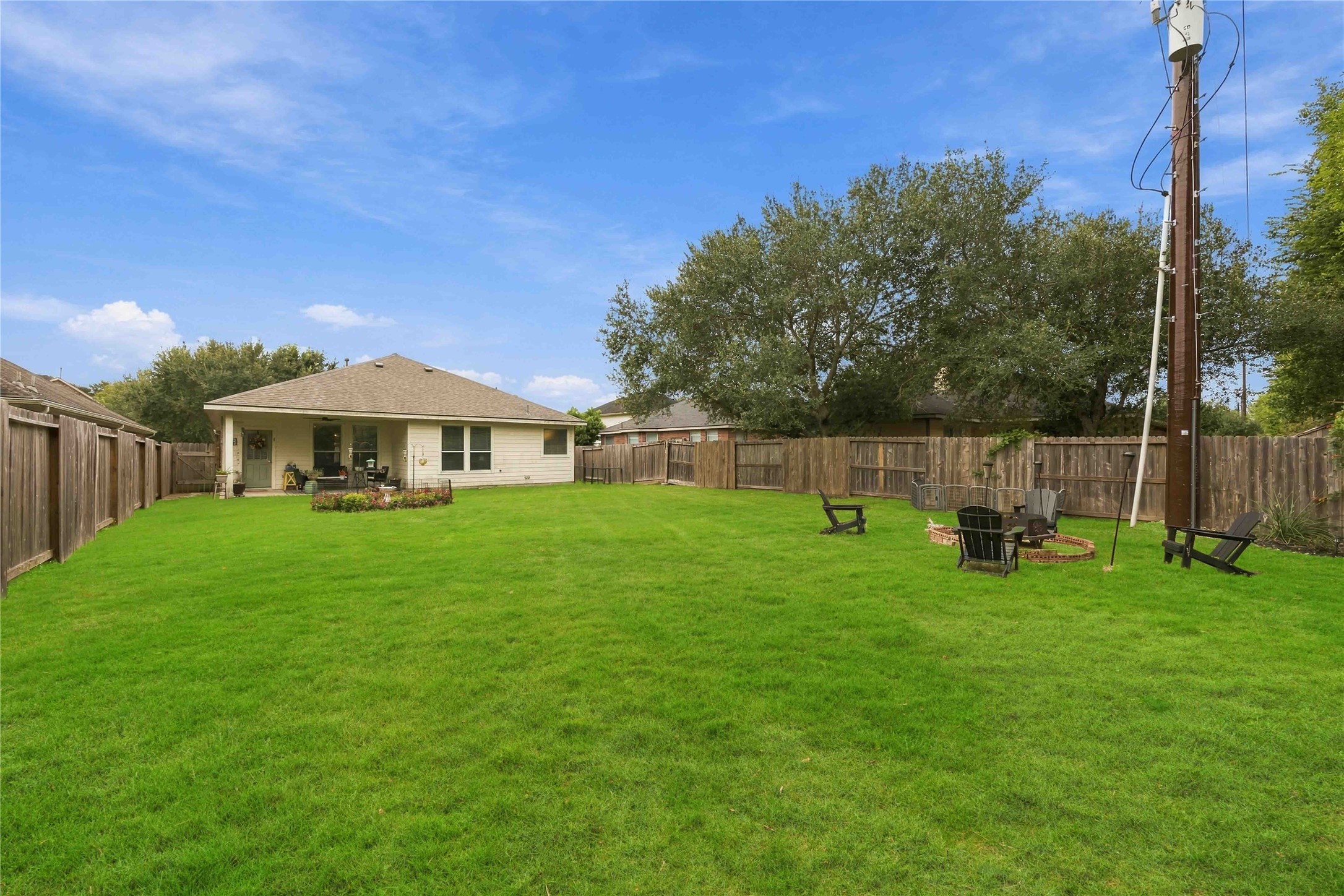 Wide backyard view highlighting the substantial lawn area and designated outdoor gathering space.
