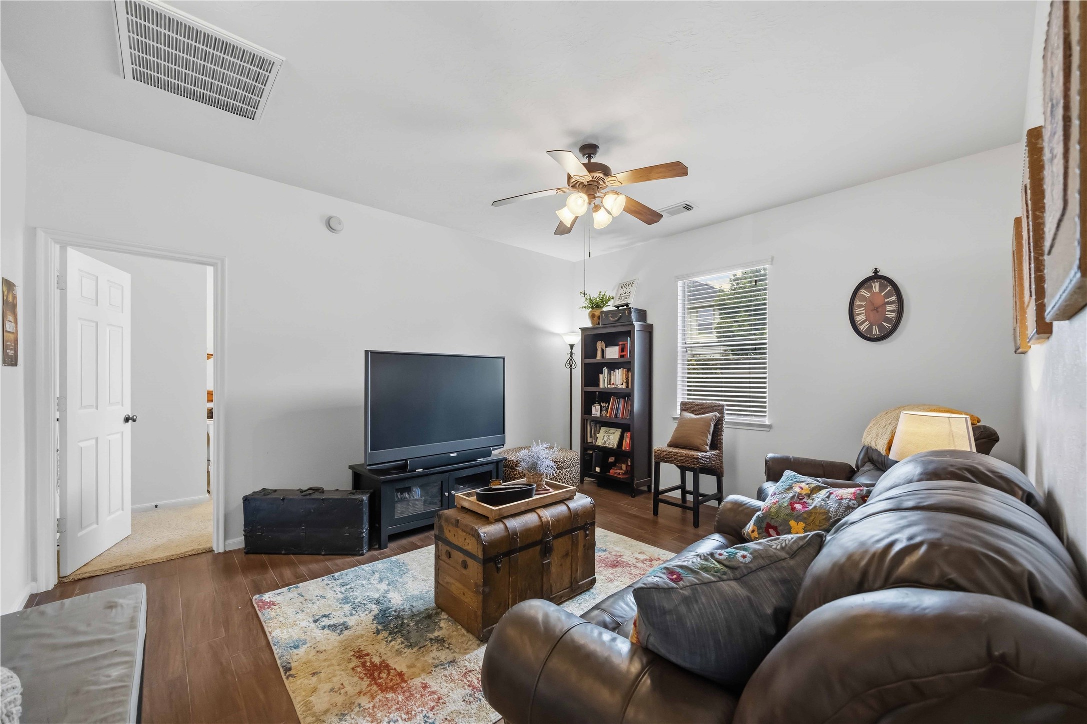 Versatile den with wood-look tile flooring, ceiling fan, and natural light, ideal for a home office or media room.