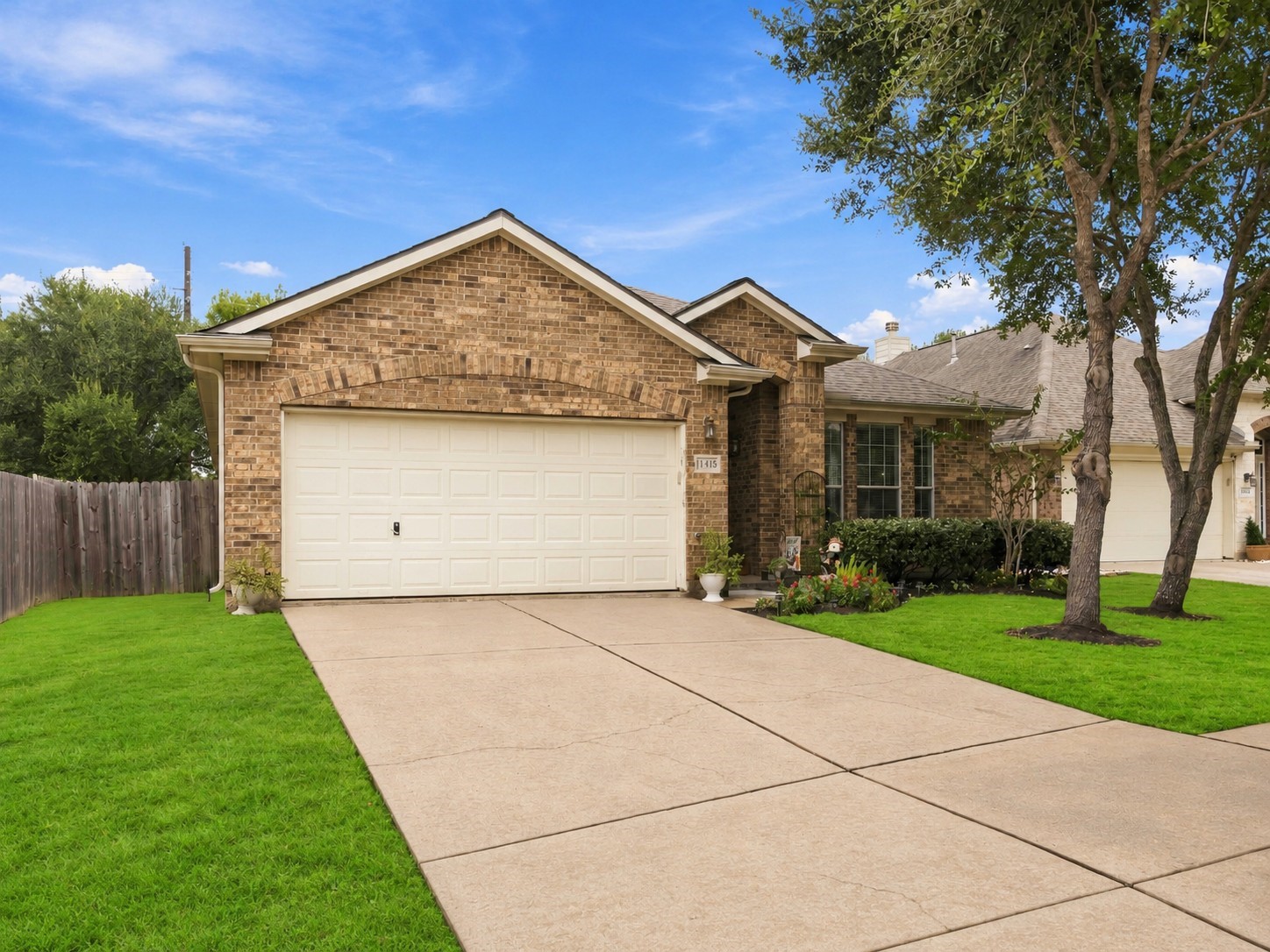 Charming single-story brick home with a two-car garage, mature trees, and a spacious front lawn.