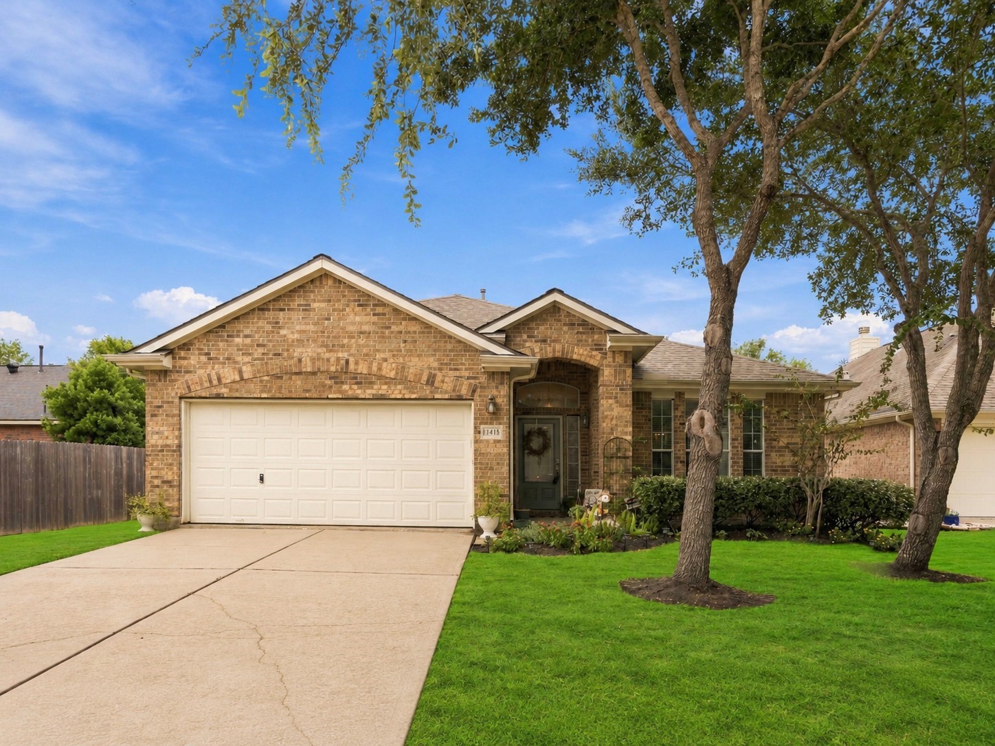 Attractive brick exterior with a wide driveway and beautifully maintained front yard.