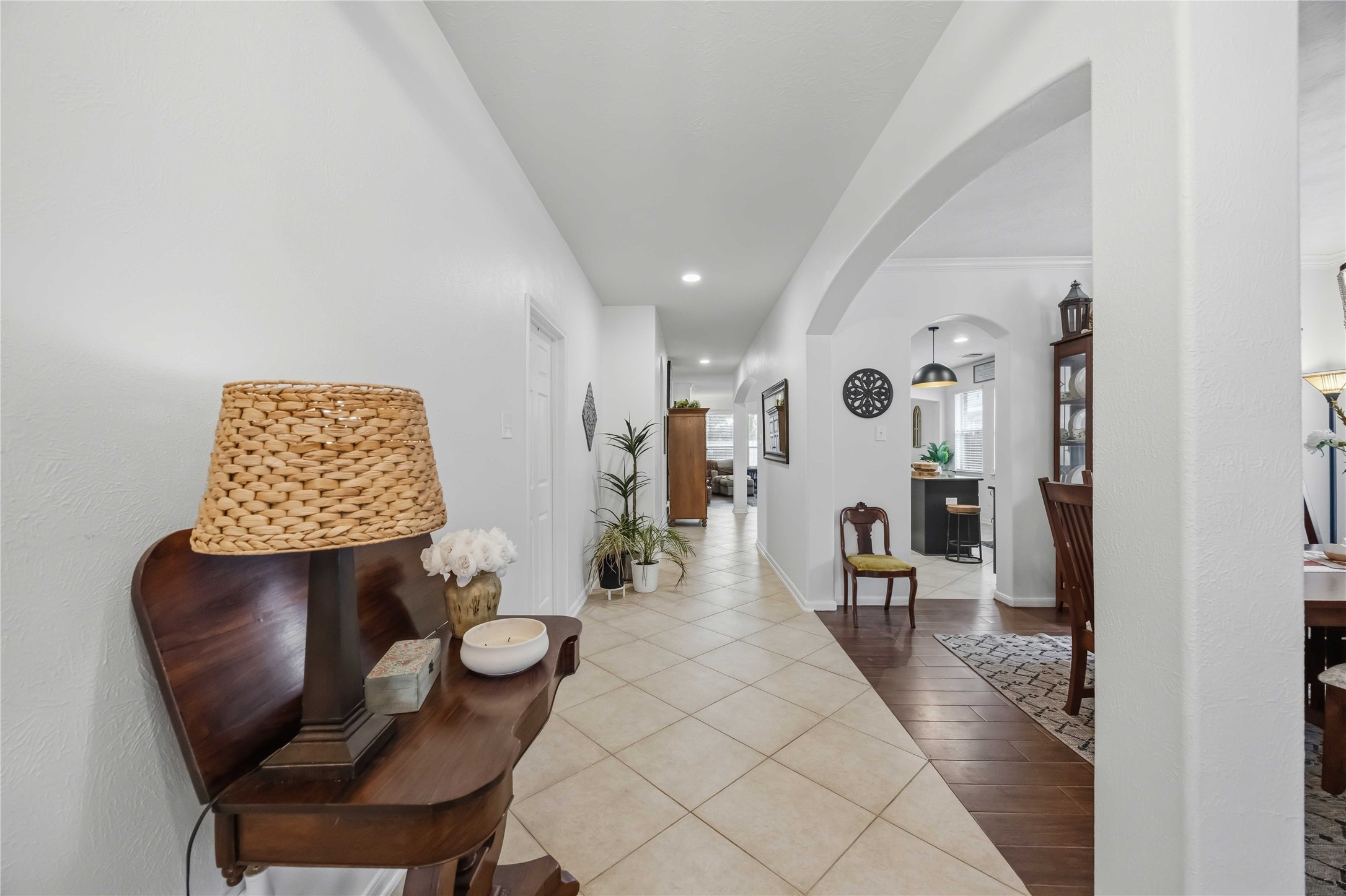 Extended entry hallway featuring neutral tile flooring and arched openings connecting the living spaces.