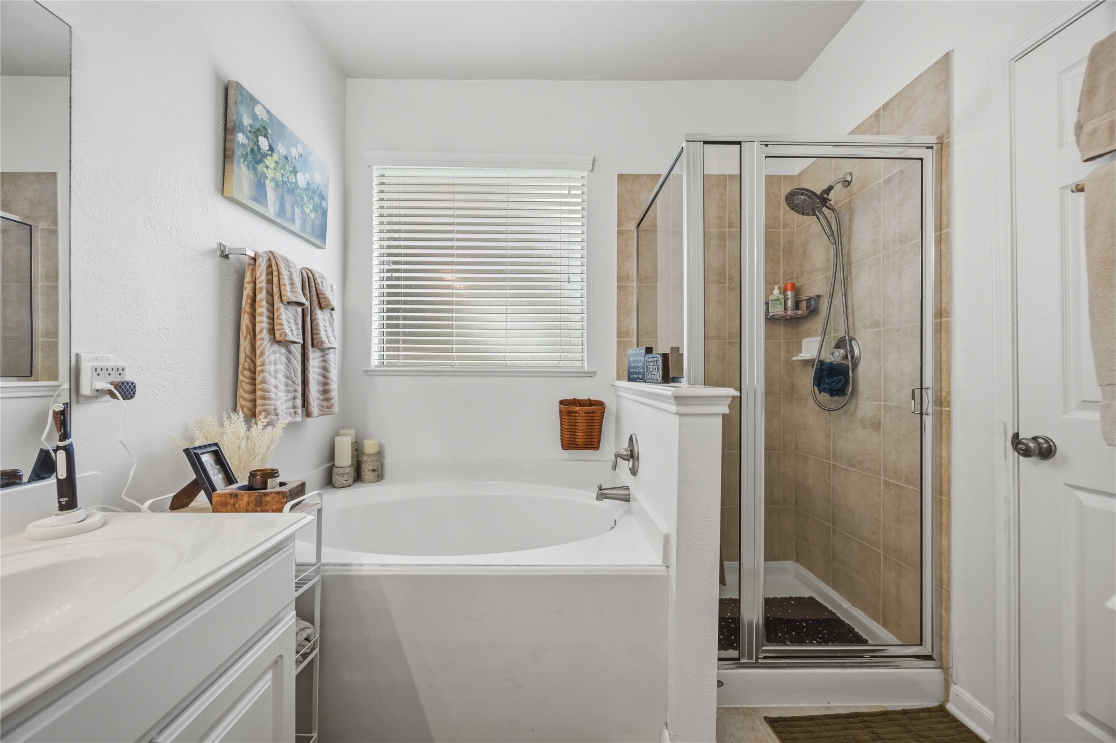 Enjoy a separate soaking tub and glass-enclosed shower with tiled walls in the primary bathroom.