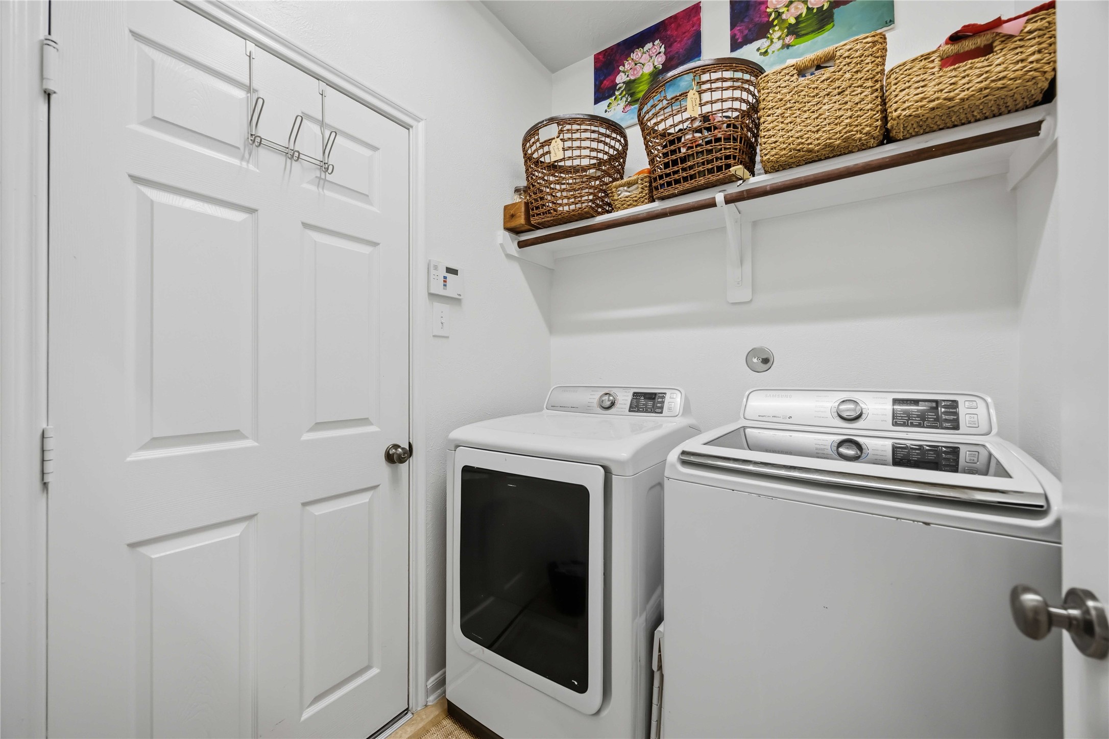 Convenient laundry room with full-size washer and dryer space and overhead shelving for extra storage.