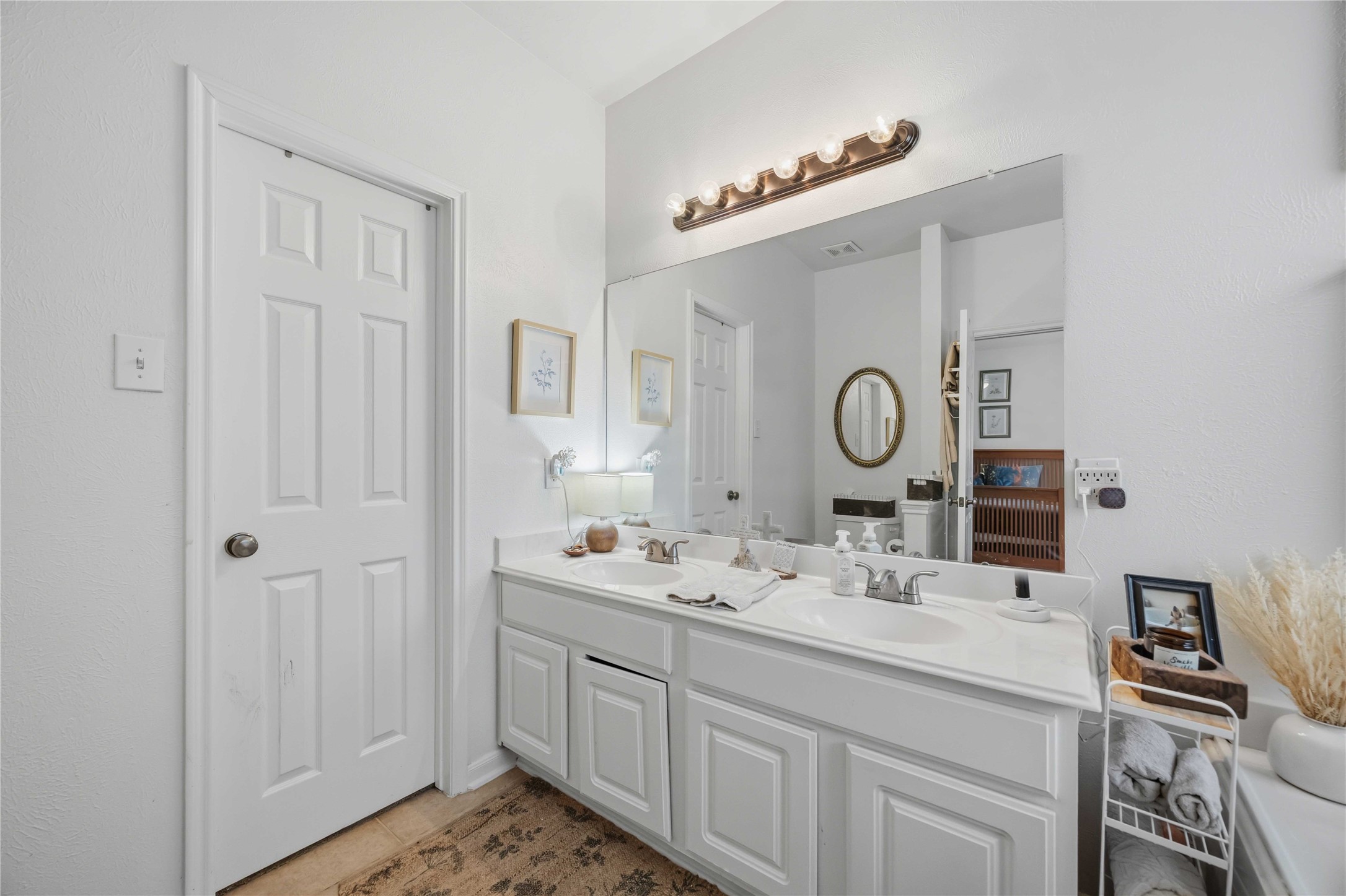 Primary bathroom features a dual-sink vanity, expansive wall mirror, and ample under-sink storage.