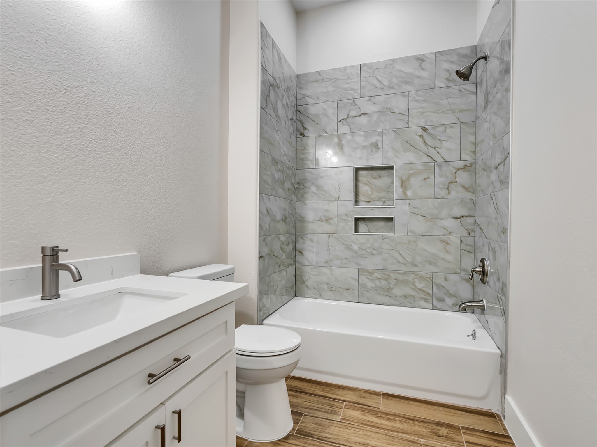 Hall Bath with quartz countertops and tiled shower.