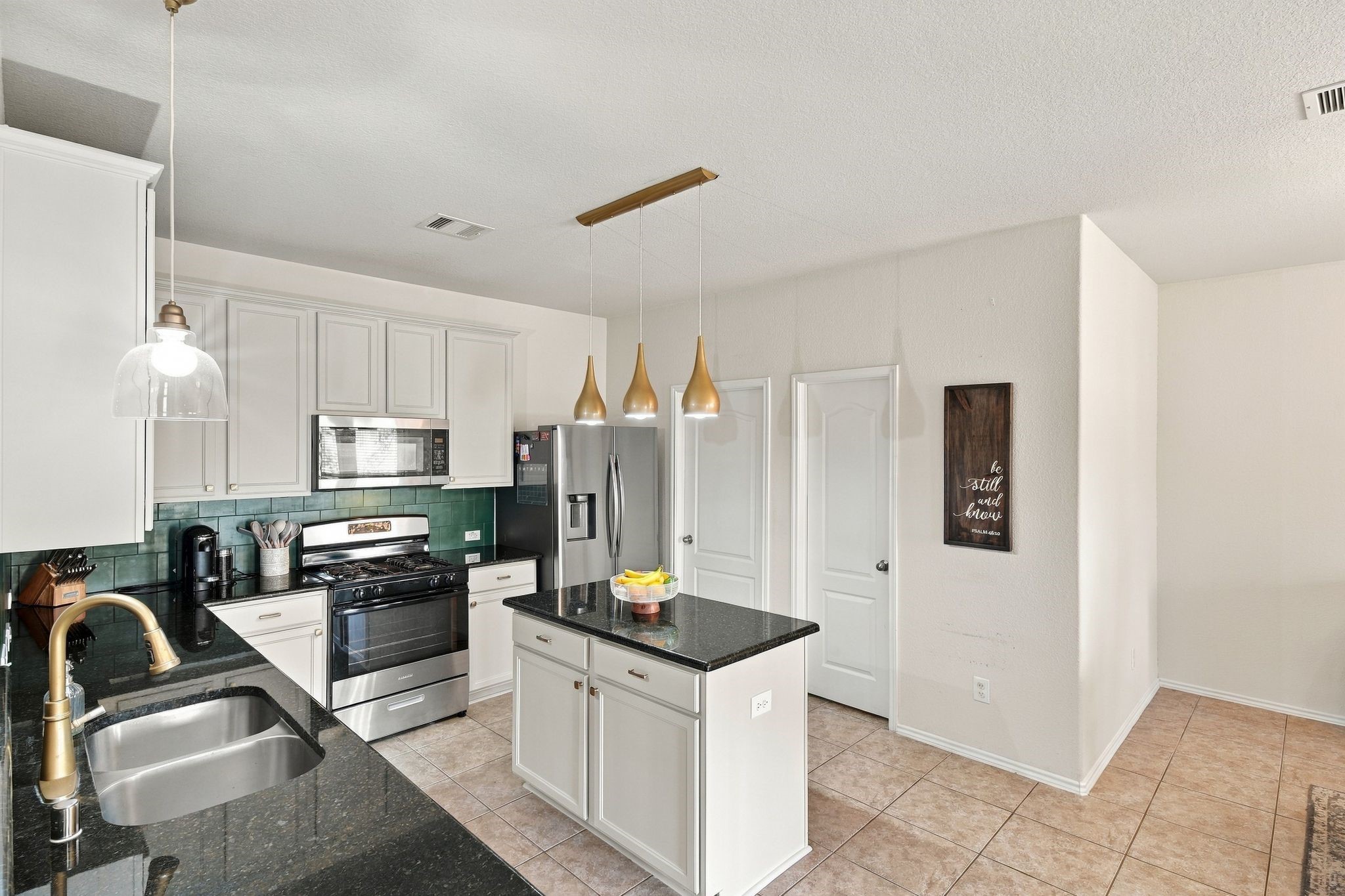 Modern kitchen with sleek black countertops, stainless steel appliances, and stylish pendant lighting.