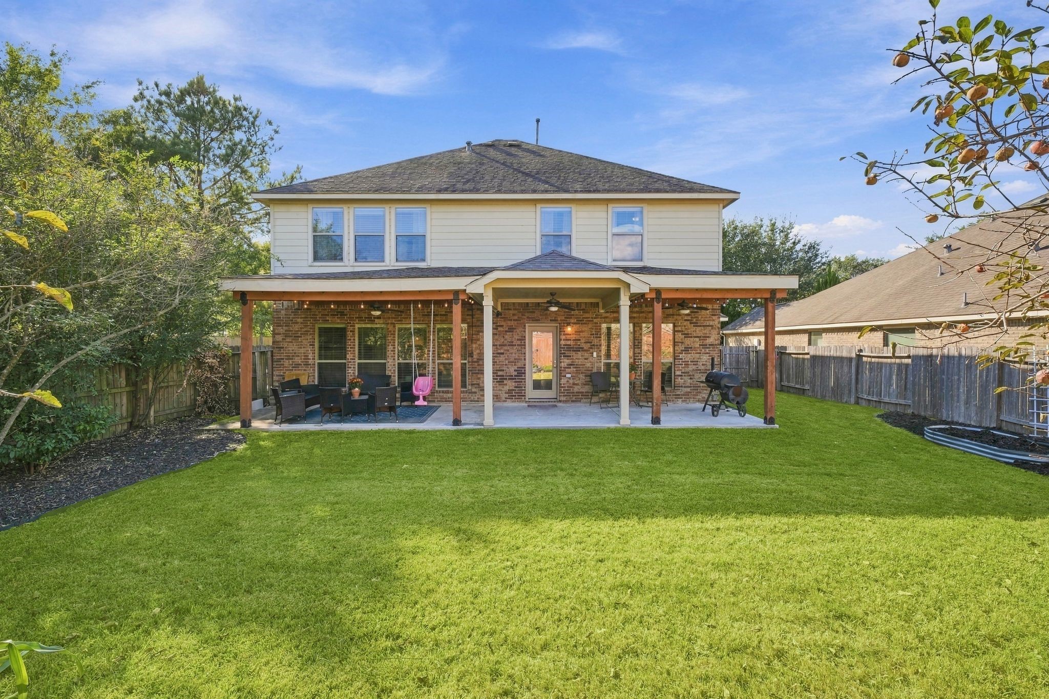 Charming two-story home with a spacious covered patio overlooking a lush, well-manicured backyard, perfect for outdoor entertaining and relaxation.