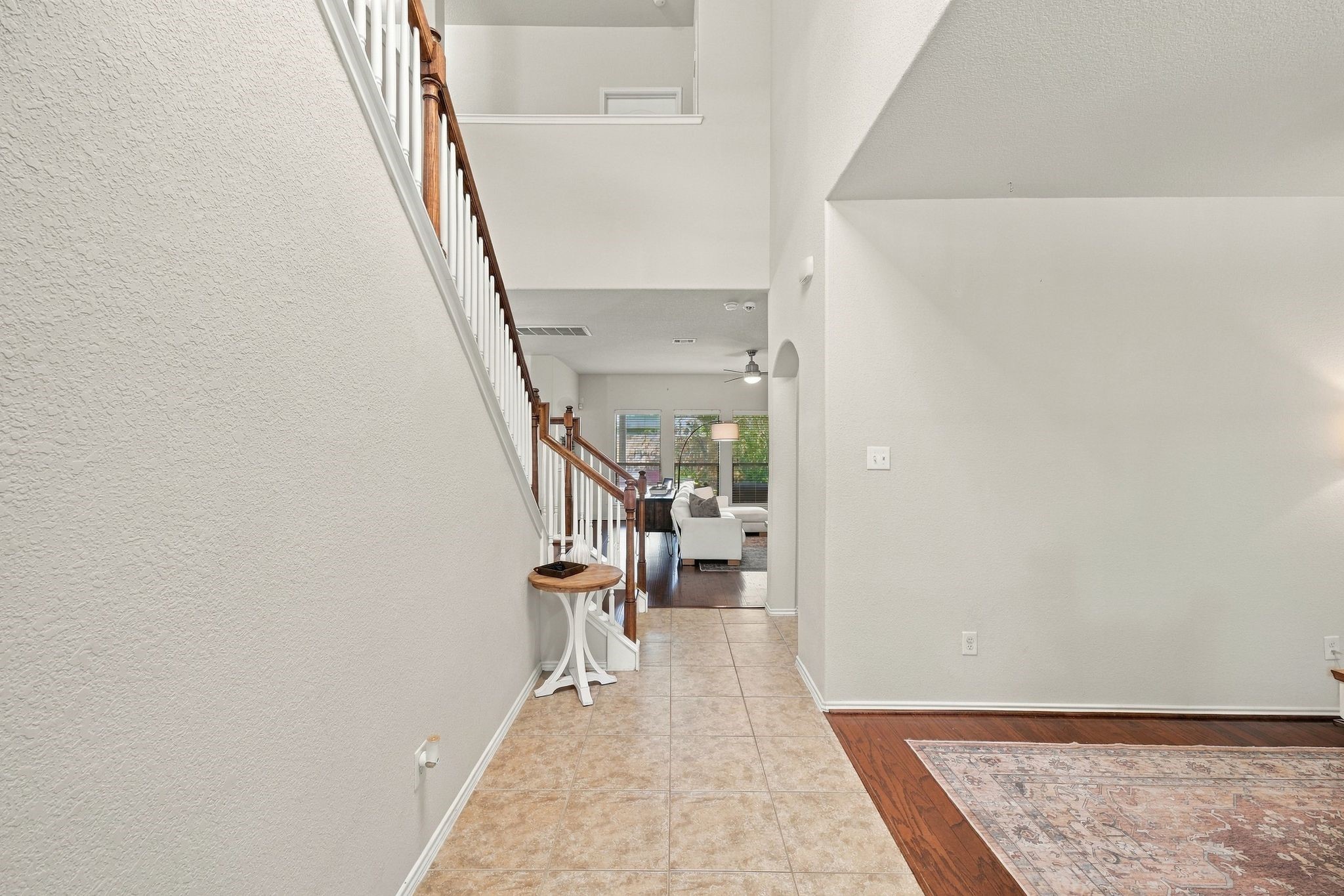 Bright and welcoming entryway with elegant tile flooring, leading to a spacious living area and featuring a stylish staircase.