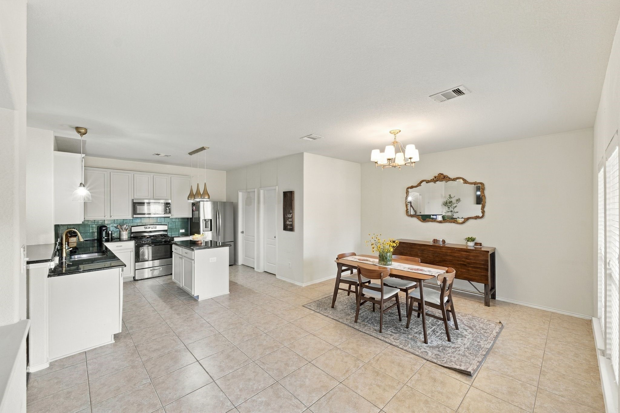Spacious open-concept kitchen and dining area with modern stainless steel appliances, sleek white cabinetry, and elegant tile flooring, perfect for entertaining.