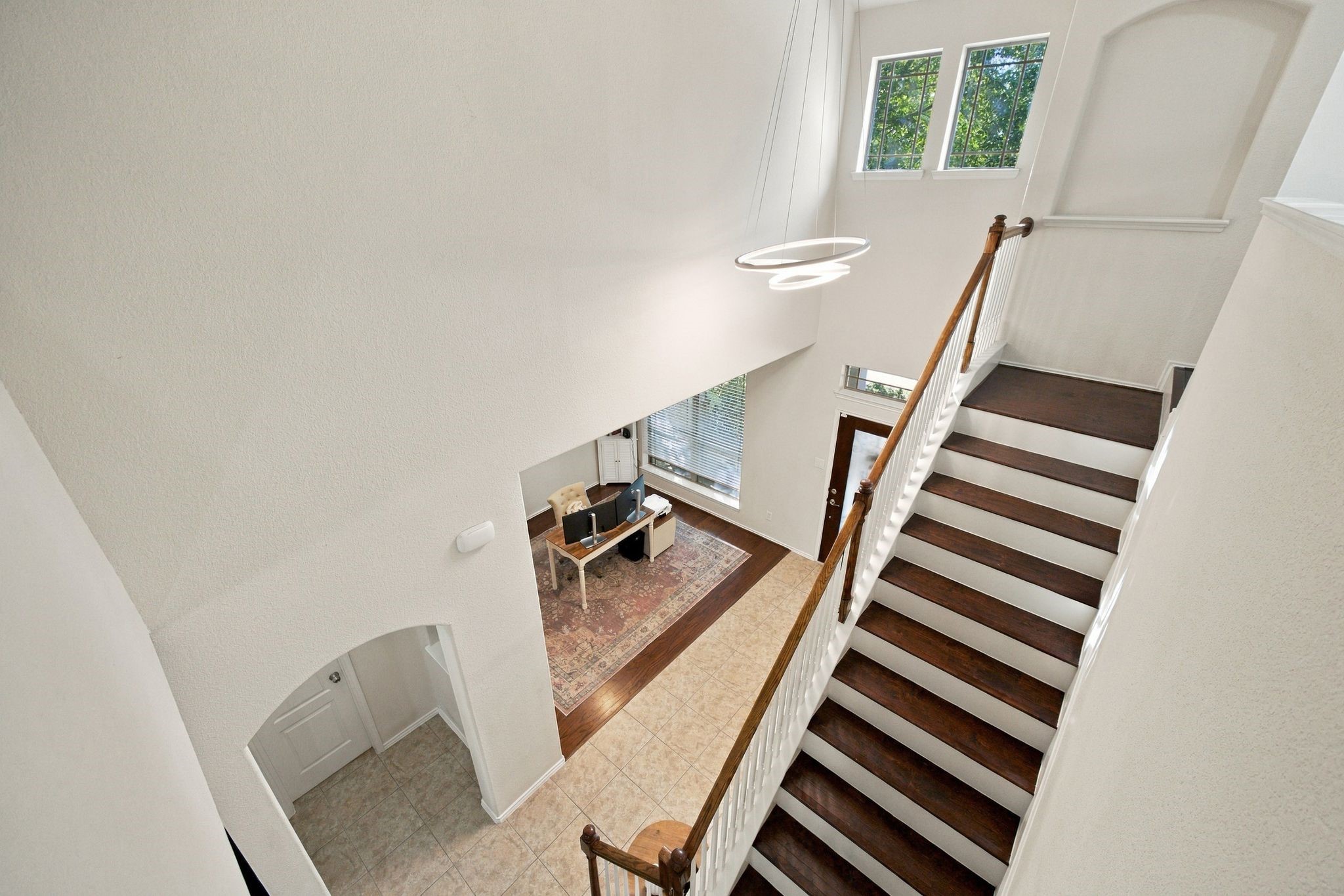 Elegant foyer with soaring ceilings and a grand staircase leading to the upper level, featuring modern lighting and abundant natural light from large windows.