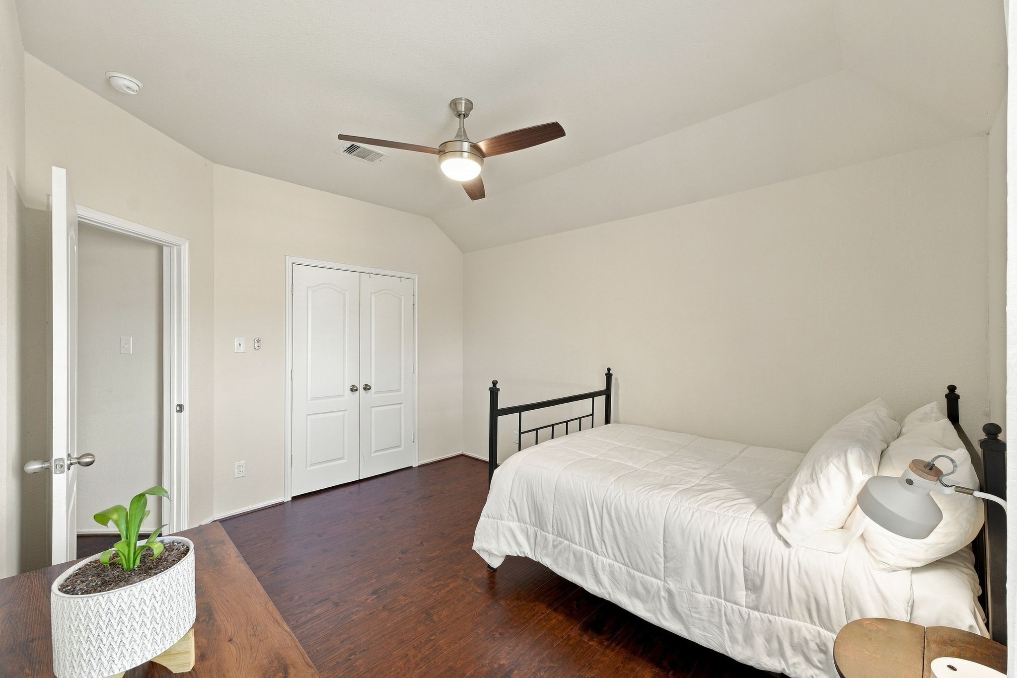 Cozy bedroom with sleek hardwood floors, a ceiling fan, and ample closet space, perfect for relaxation.