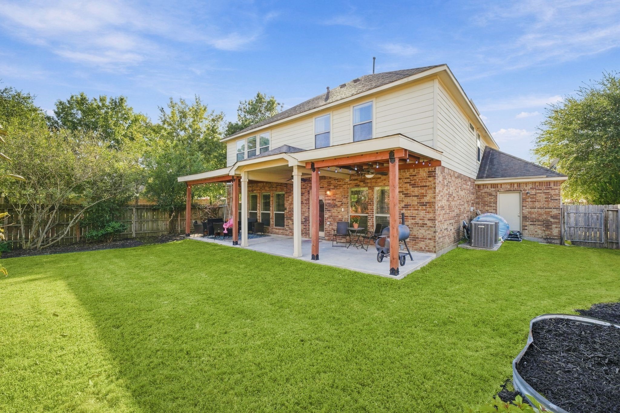 Charming two-story home with a spacious backyard, featuring a covered patio perfect for outdoor entertaining, surrounded by lush greenery for added privacy.