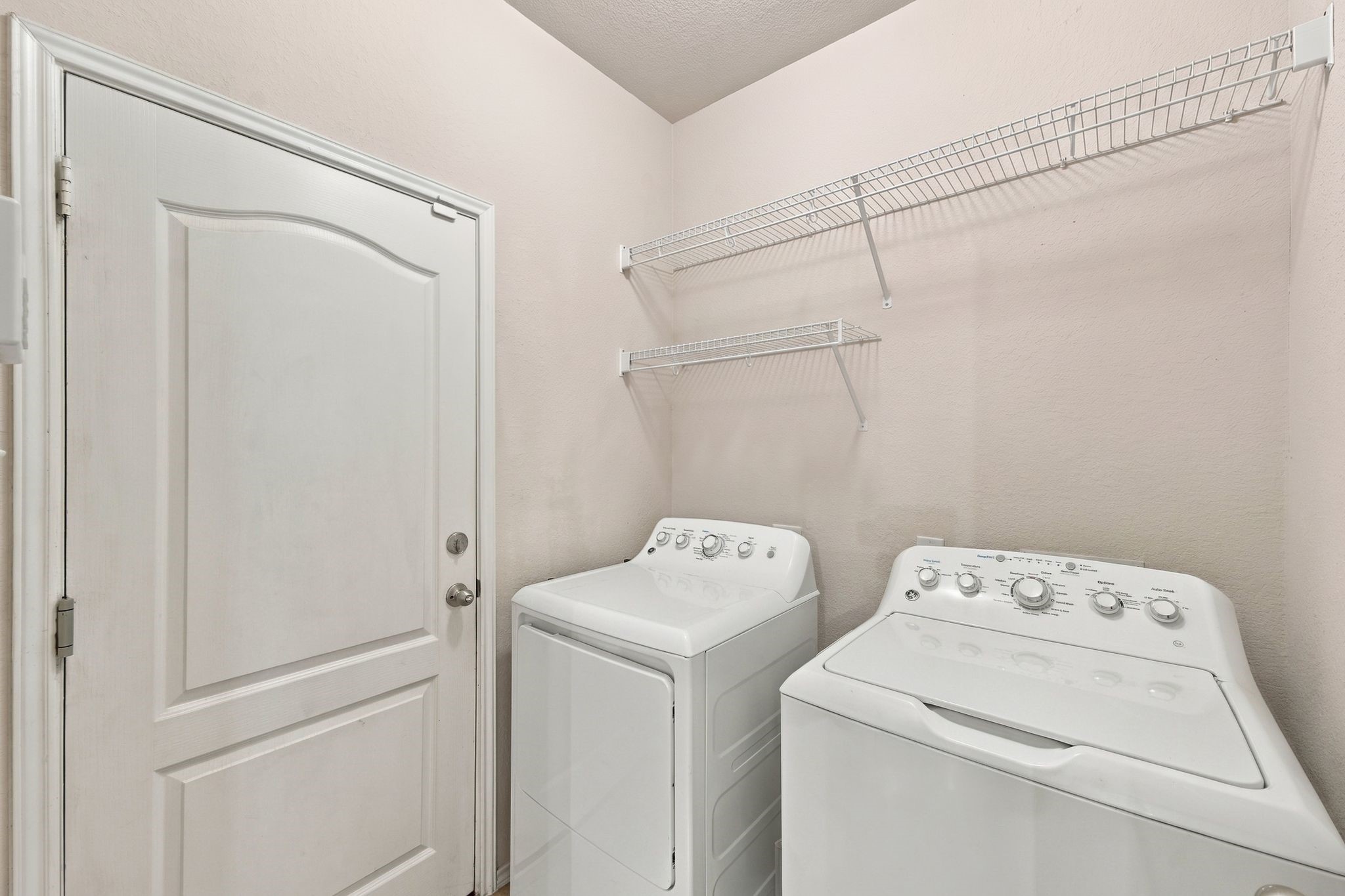 Convenient laundry room equipped with ample shelving for storage.