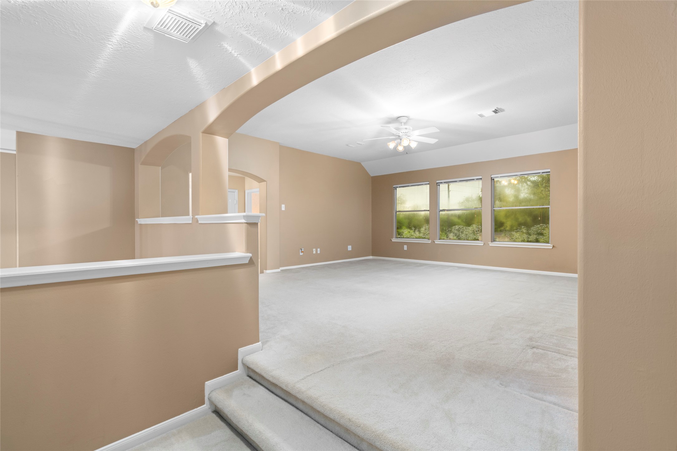 Large upstairs game room with soft carpeting, abundant natural light, and architectural archways that add character. This flexible second living space gives the home an important advantage for households wanting separation between everyday living, entertaining, and private spaces.