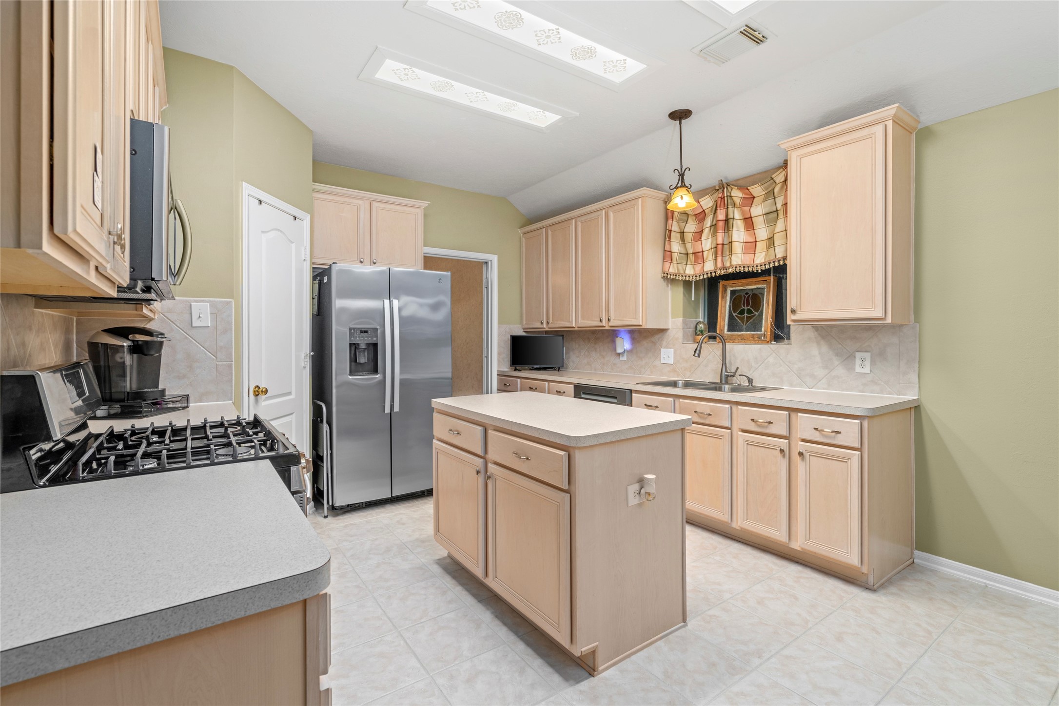 Well-planned kitchen featuring a central island, generous cabinetry, natural light, and a convenient window nook. The layout provides room for food preparation, storage, and casual interaction while maintaining an inviting connection to the rest of the home.
