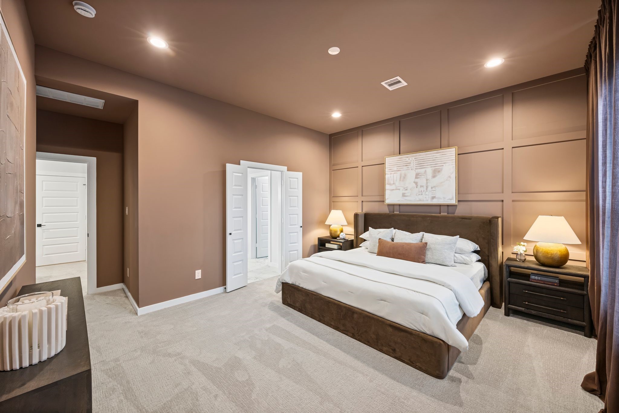 Step into the serene elegance of the primary bedroom, featuring warm tones, plush carpeting, and sophisticated paneling for a perfect retreat. **Model Home of similar layout & finishes.**