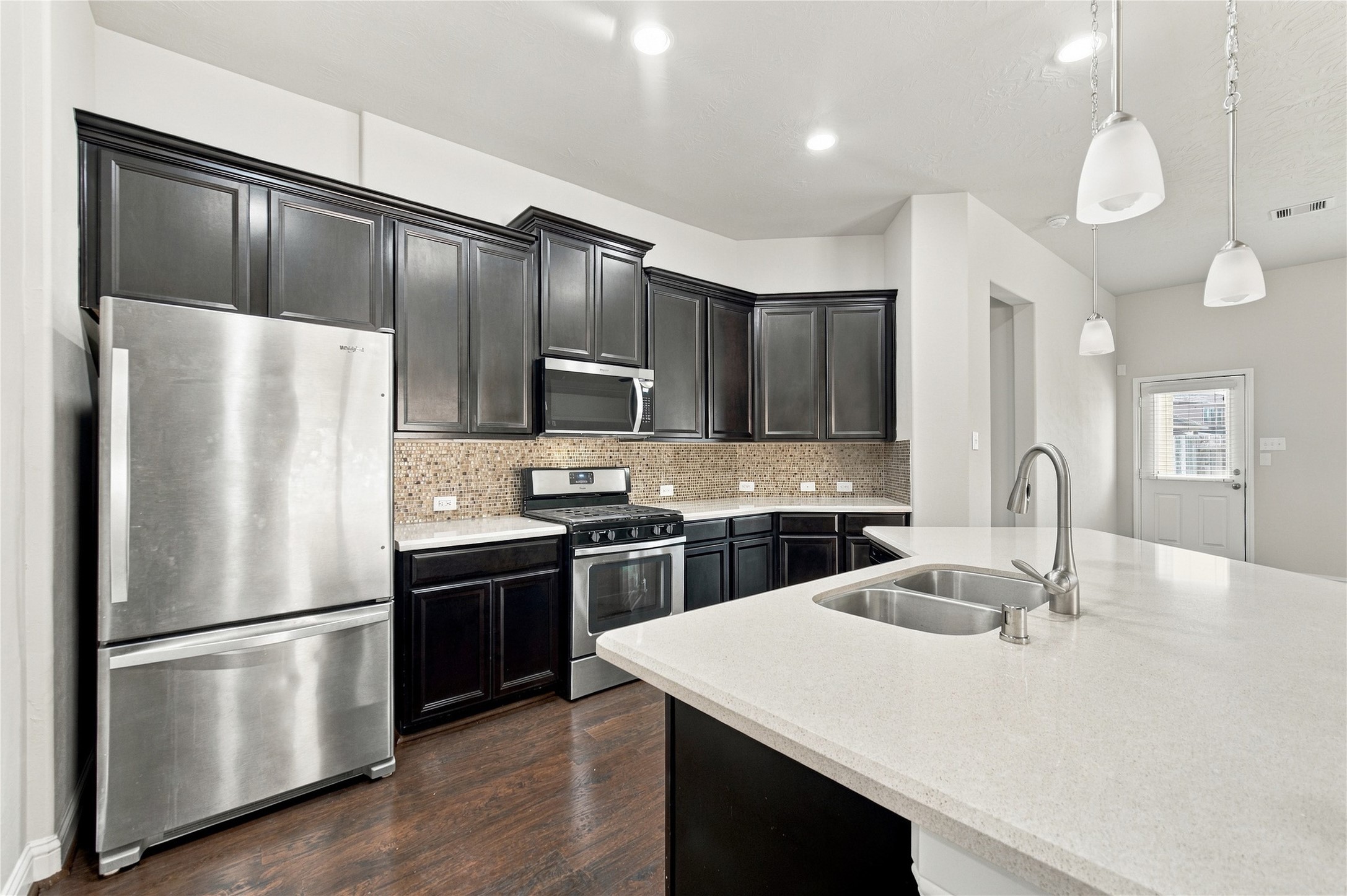 The kitchen features stainless steel appliances, rich espresso-colored maple cabinetry, elegant Silestone countertops, and beautiful tile backsplash. kitchen complete with stainless steel appliances, rich espresso-colored maple cabinetry, elegant Silestone countertops, and beautiful tile backsplash.